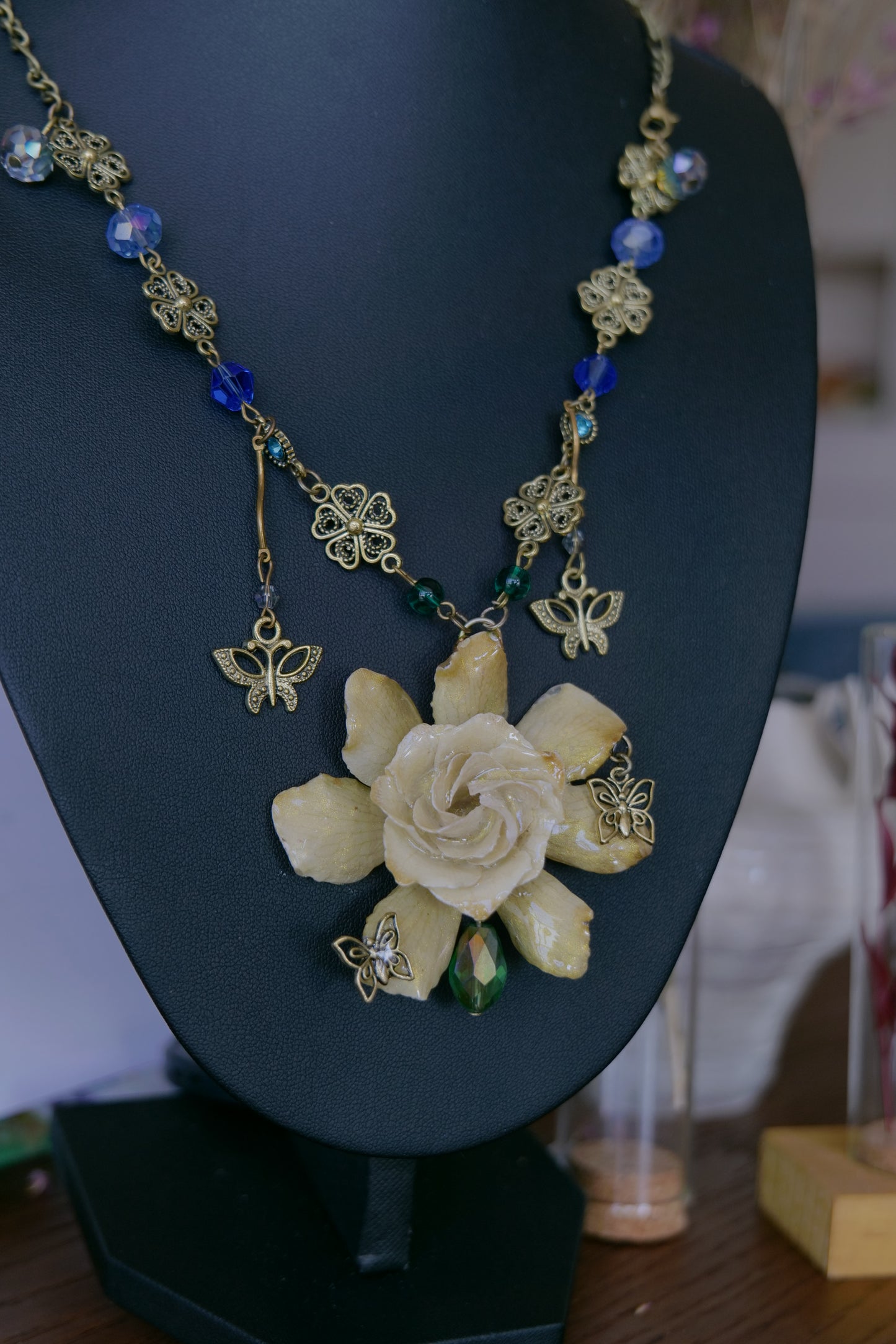 Additional detail of butterfly drops and garden-inspired ornament around the preserved gardenia