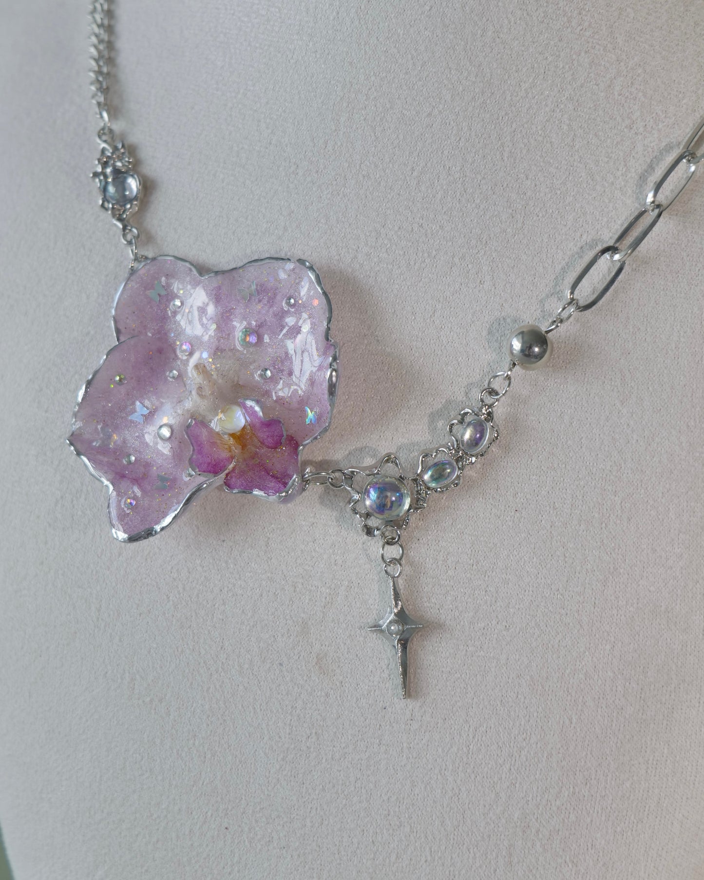 Detailed view of asymmetric chain sections beside the lilac Phalaenopsis pendant