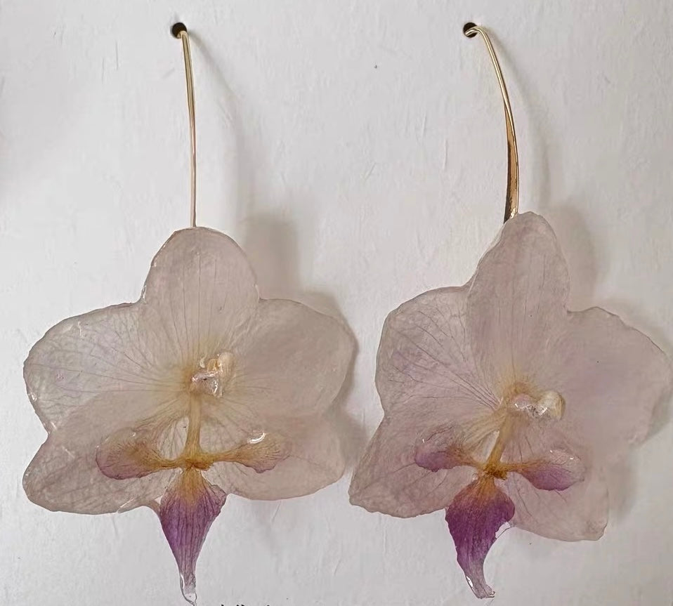 Cream white orchid ear hook earrings with translucent resin petals shown close-up by Terra Decode