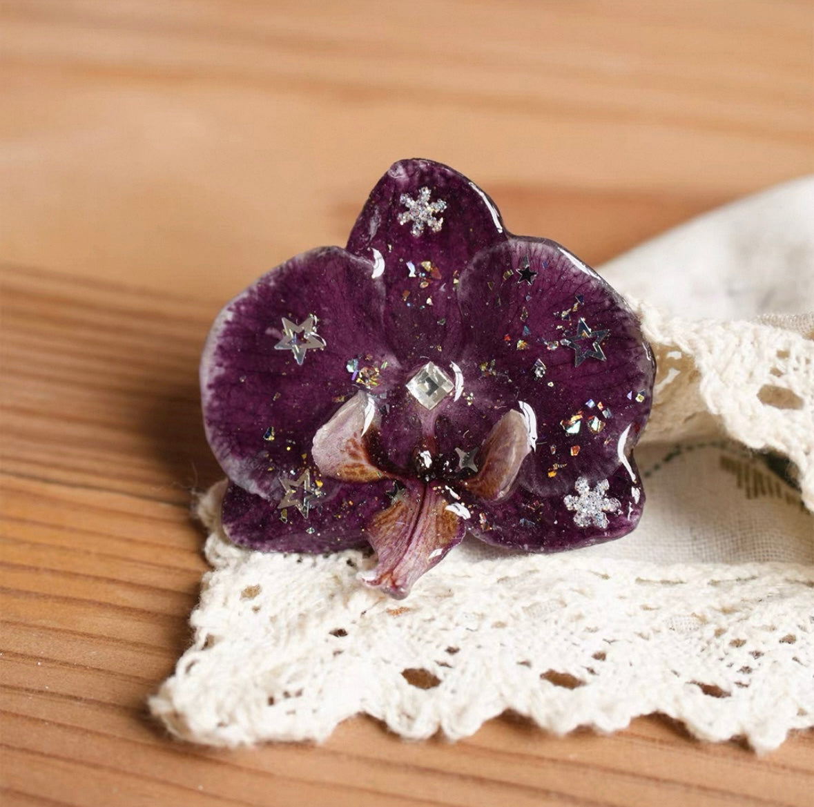 Star detail orchid brooch with deep purple resin petals and star-like accents on lace by Terra Decode