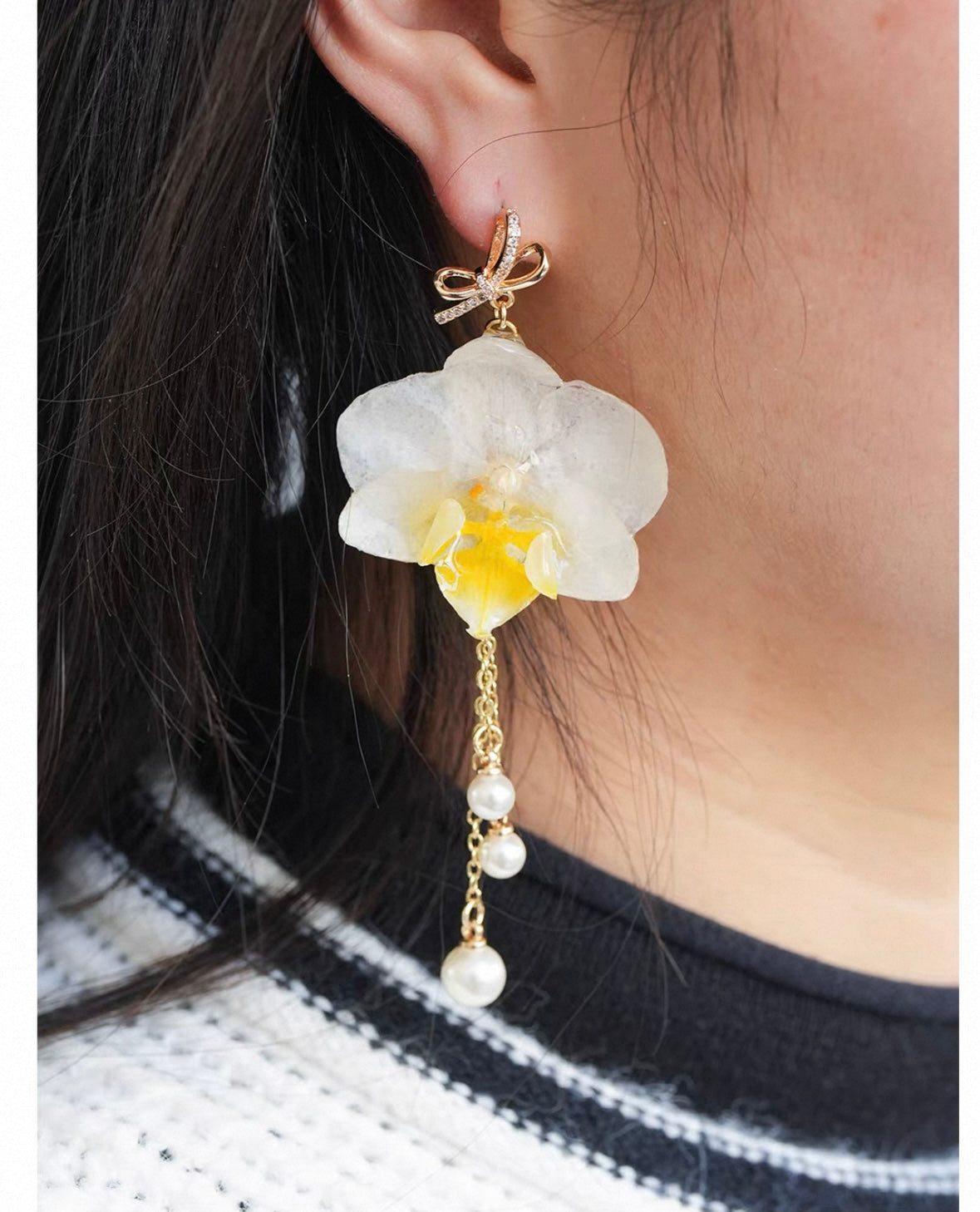 Cream white orchid earrings with resin flower petals held in hand by Terra Decode