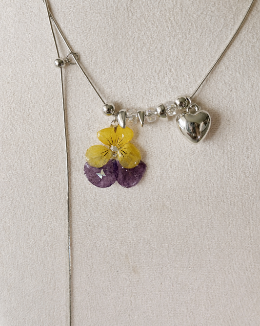 Close view of the real pansy resin pendant, clear beads and adjustable silver-toned chain, Pansy Heart Adjustable Lariat Necklace botanical jewellery by Terra Decode