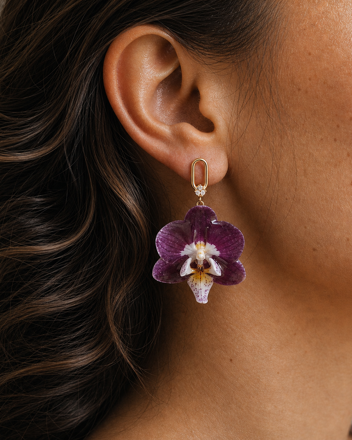 Model wearing dark purple preserved orchid drop earrings with a gold-tone geometric stud, Preserved Orchid Drop Earrings botanical jewellery by Terra Decode