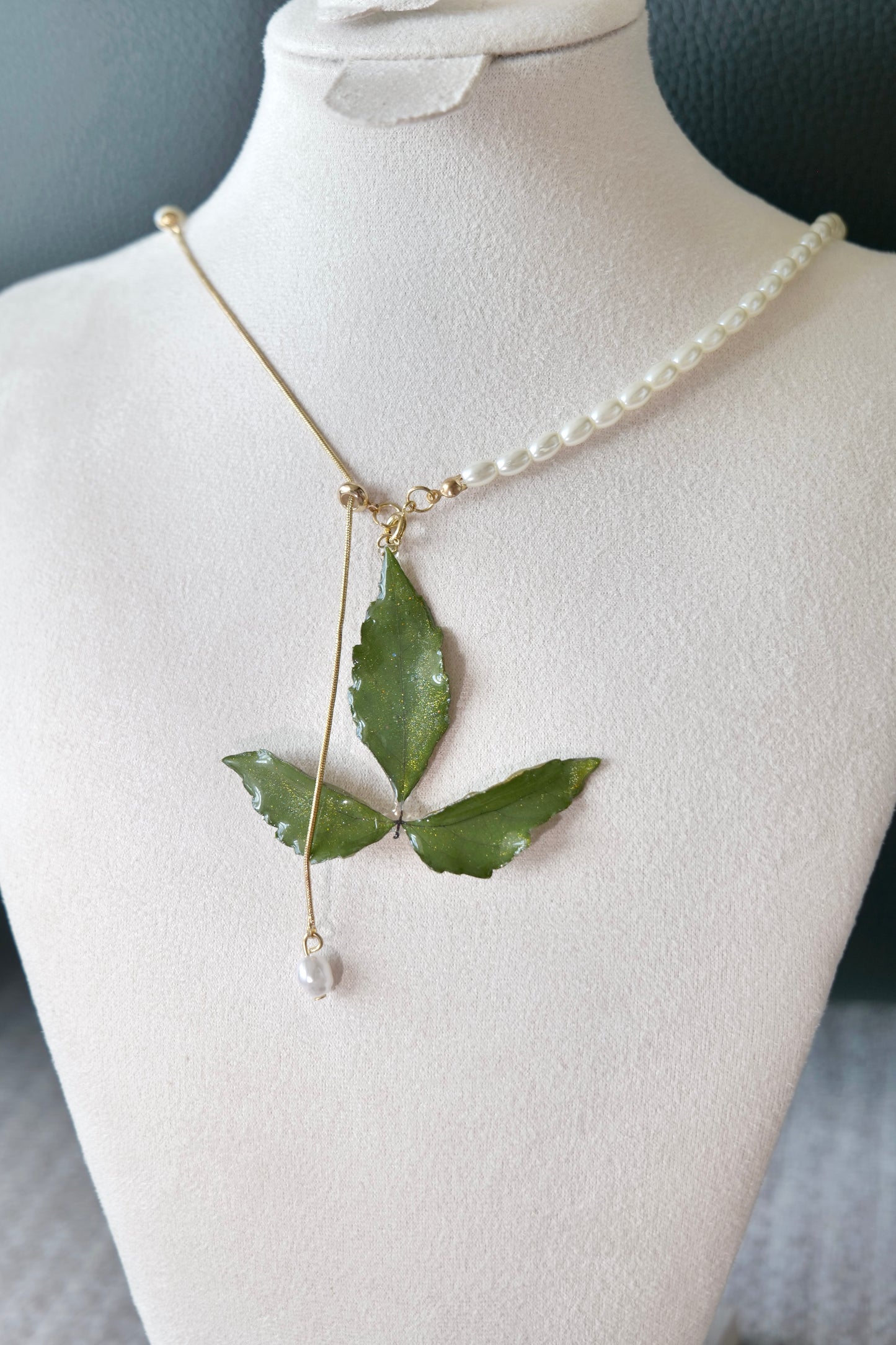 Fine detail of the clear-resin Boston ivy pendant and pearl drop