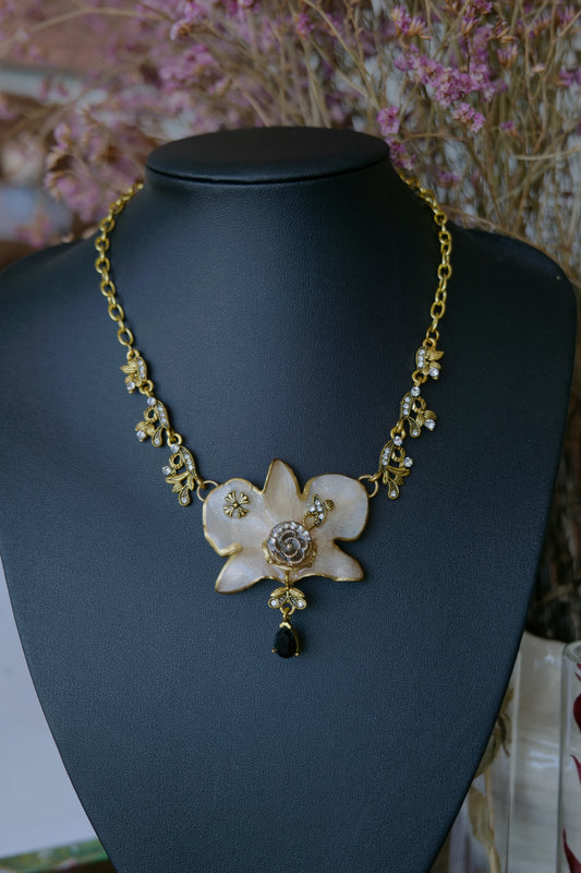 Front view of white Dendrobium necklace with antique-gold bee links and black teardrop