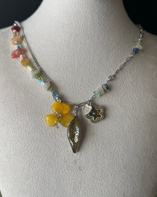 Yellow pansy and nandina leaf charm necklace with colourful beads shown from the front