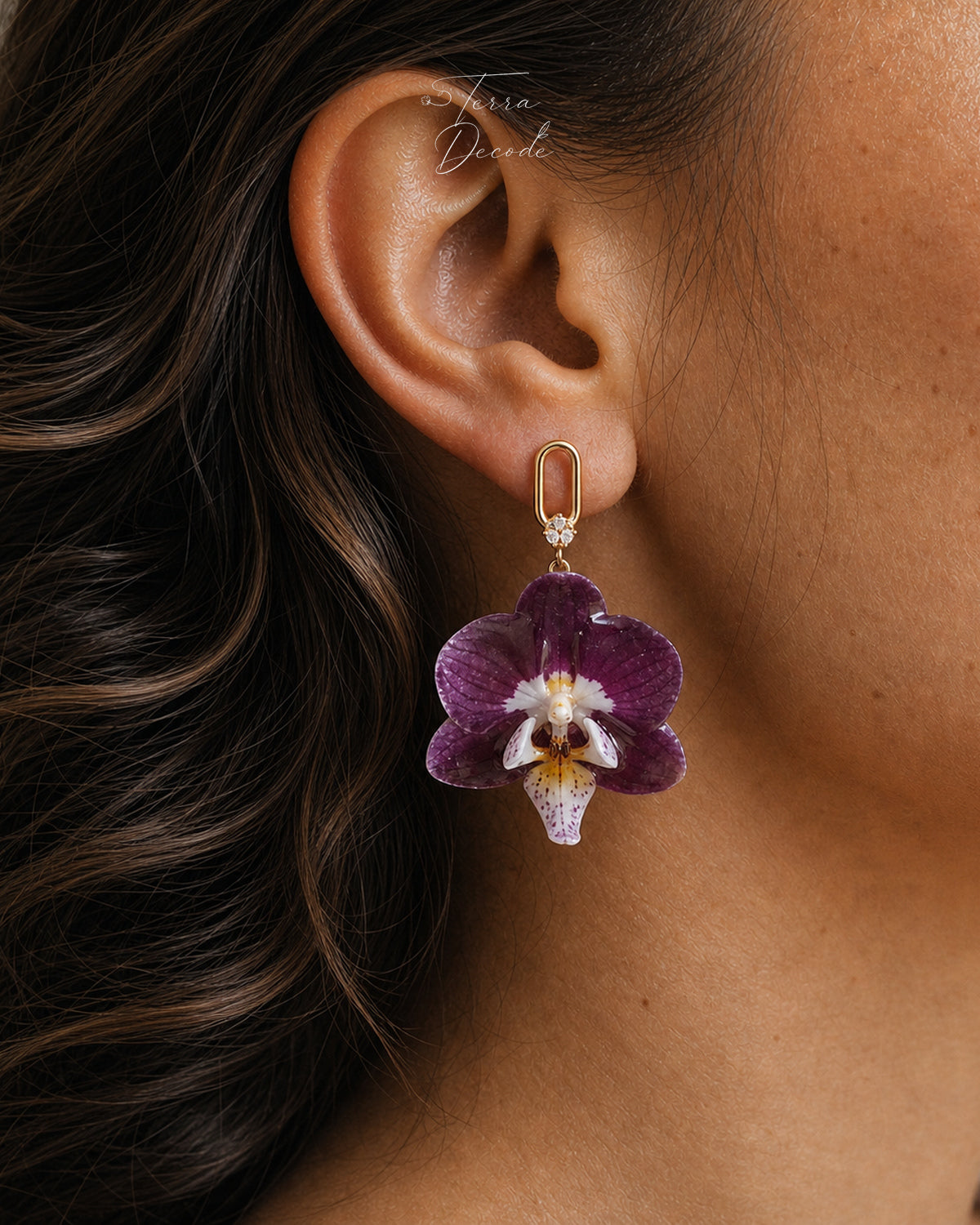 Purple orchid hook earring with resin petals and gold-tone link worn on ear by Terra Decode