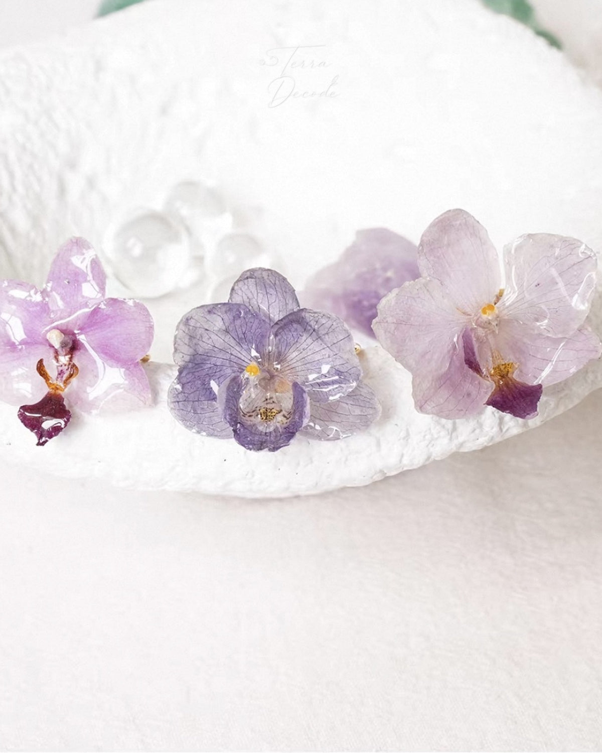Soft purple orchid ring set with resin petals arranged on a white surface by Terra Decode