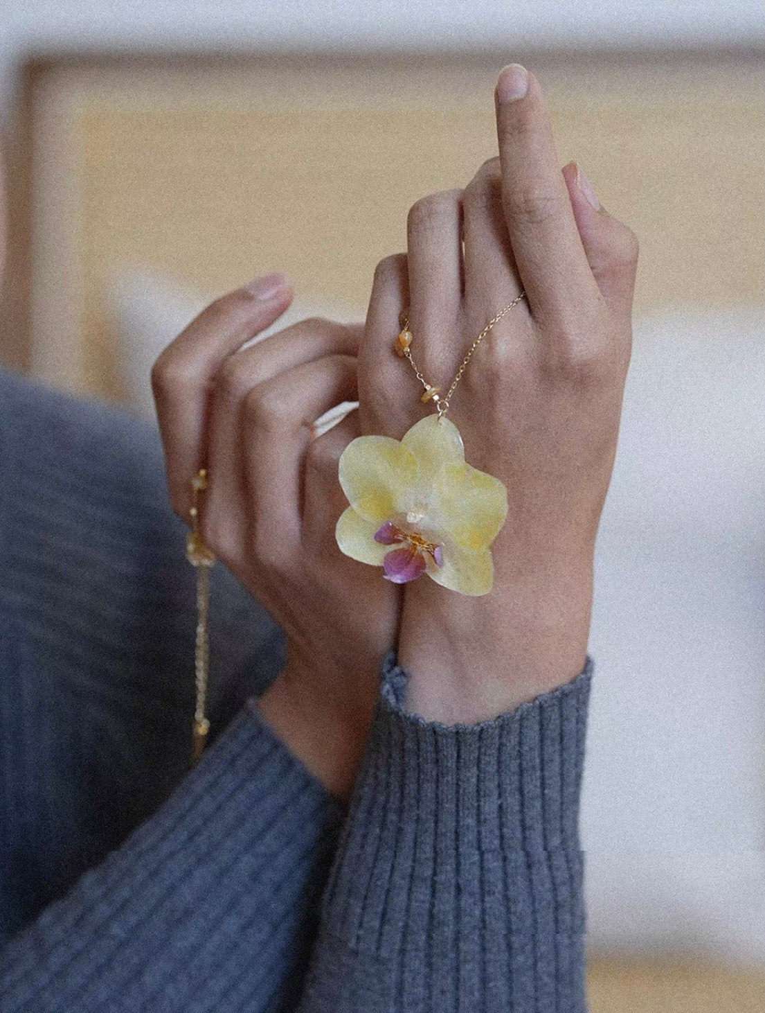Butter yellow preserved orchid pendant necklace worn on hand by Terra Decode