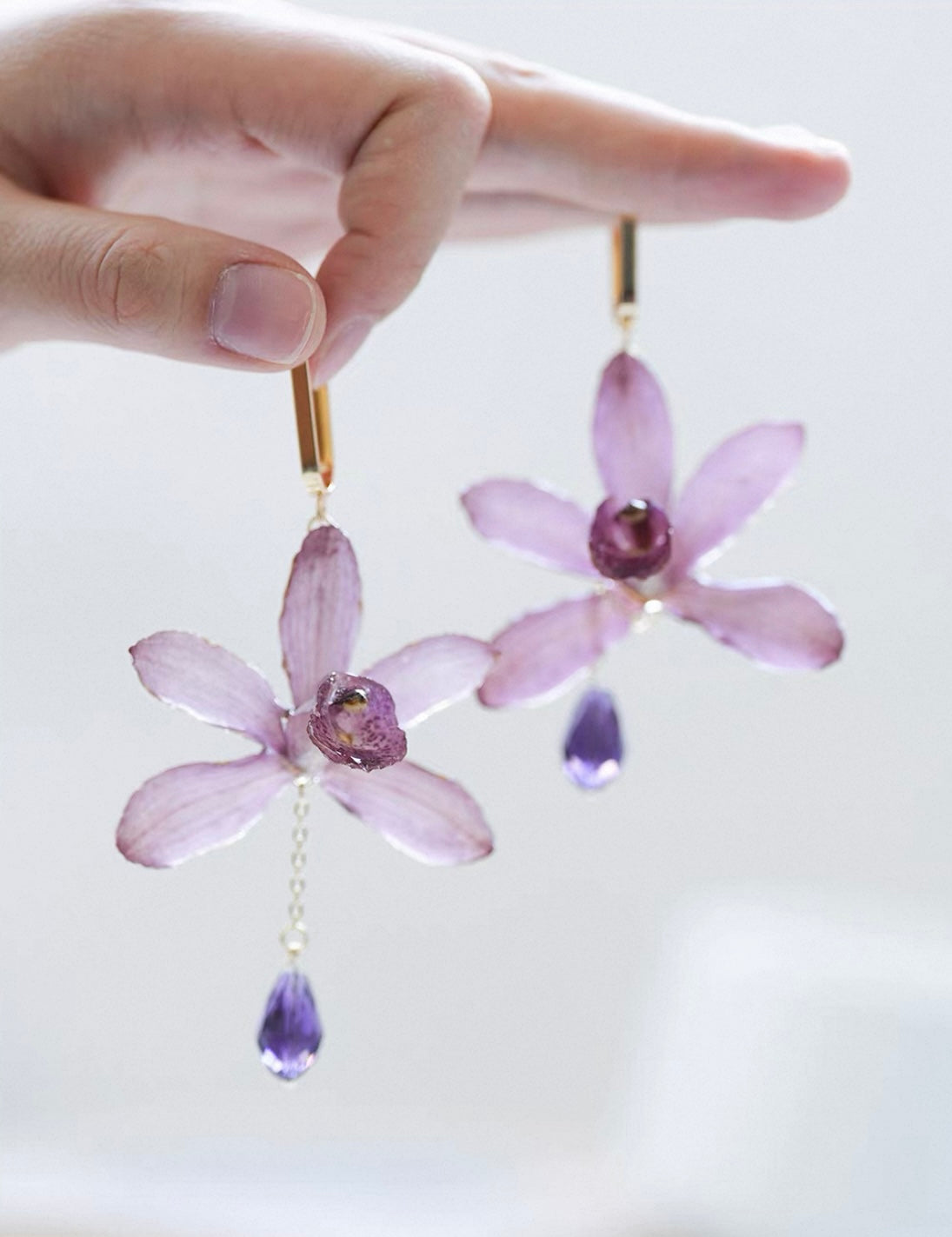 Soft purple cymbidium orchid earrings with resin petals held in hand by Terra Decode