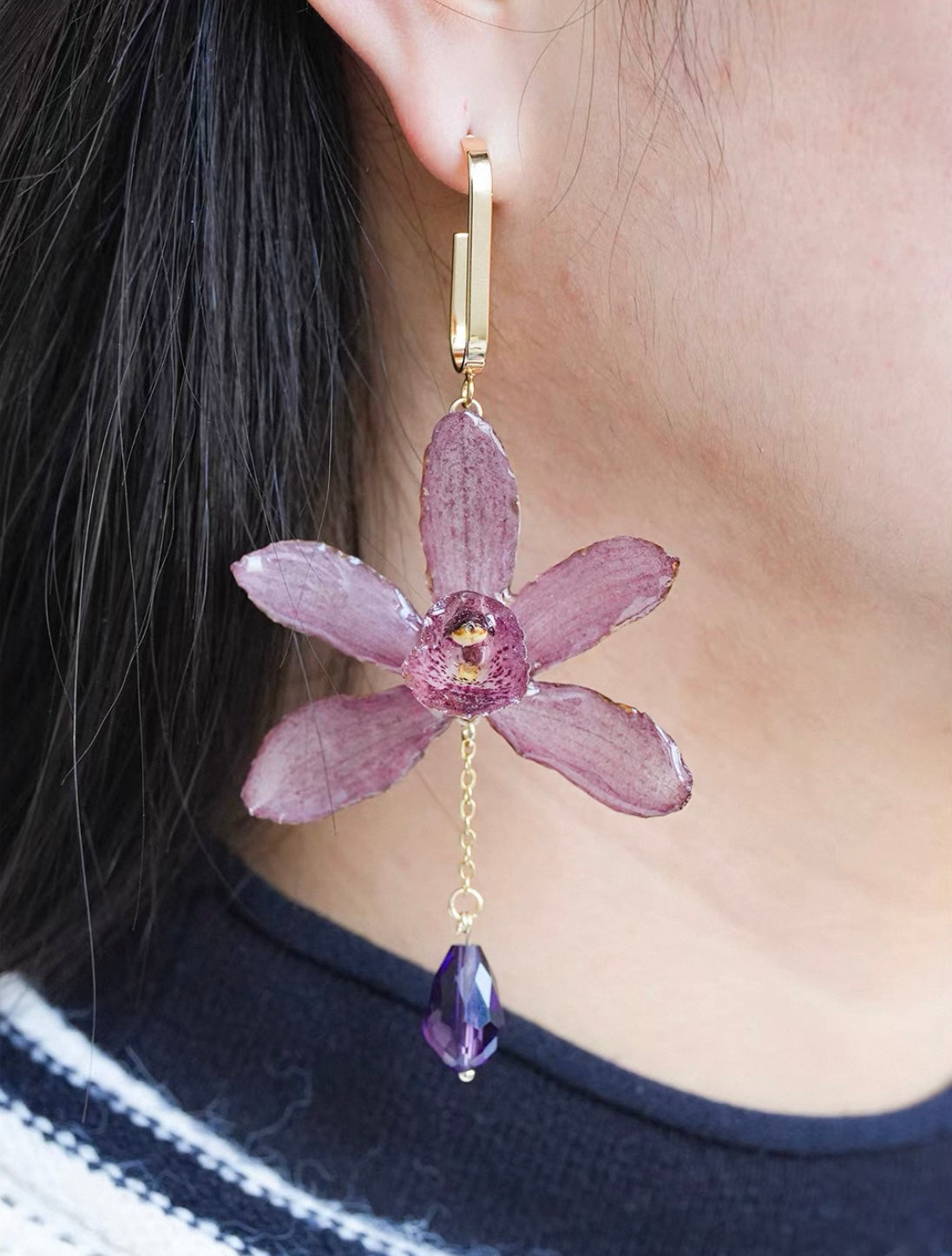 Soft purple cymbidium orchid earrings with resin petals worn on ear by Terra Decode