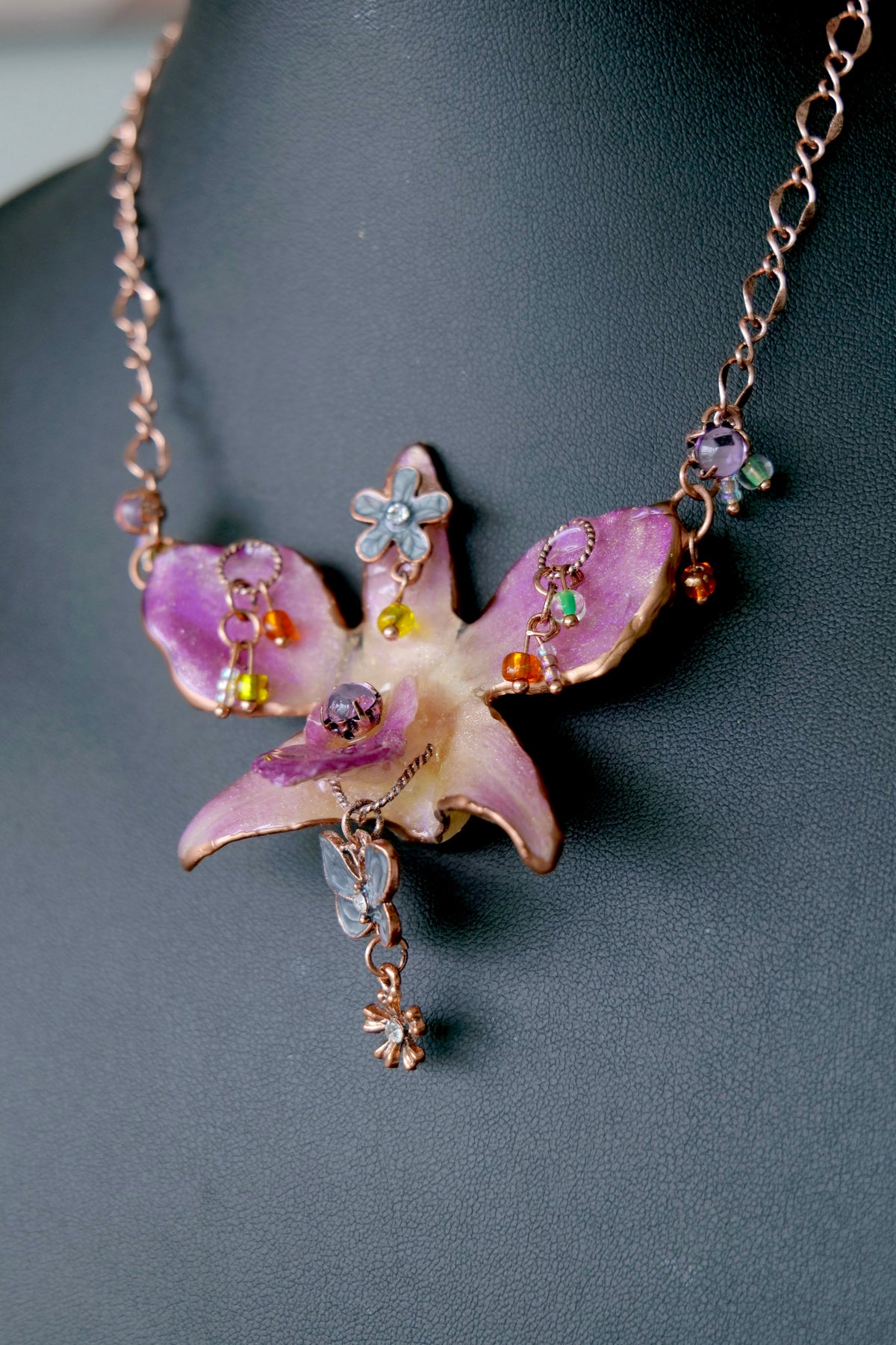 Purple preserved Dendrobium orchid necklace with rose-gold chain, pastel beads and vintage charm details.