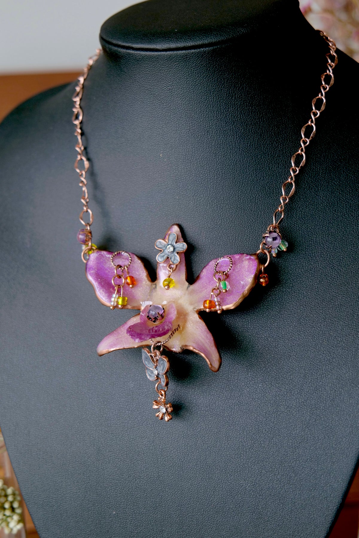 Handmade purple Dendrobium orchid necklace with antique rose-gold chain and colourful glass bead accents.
