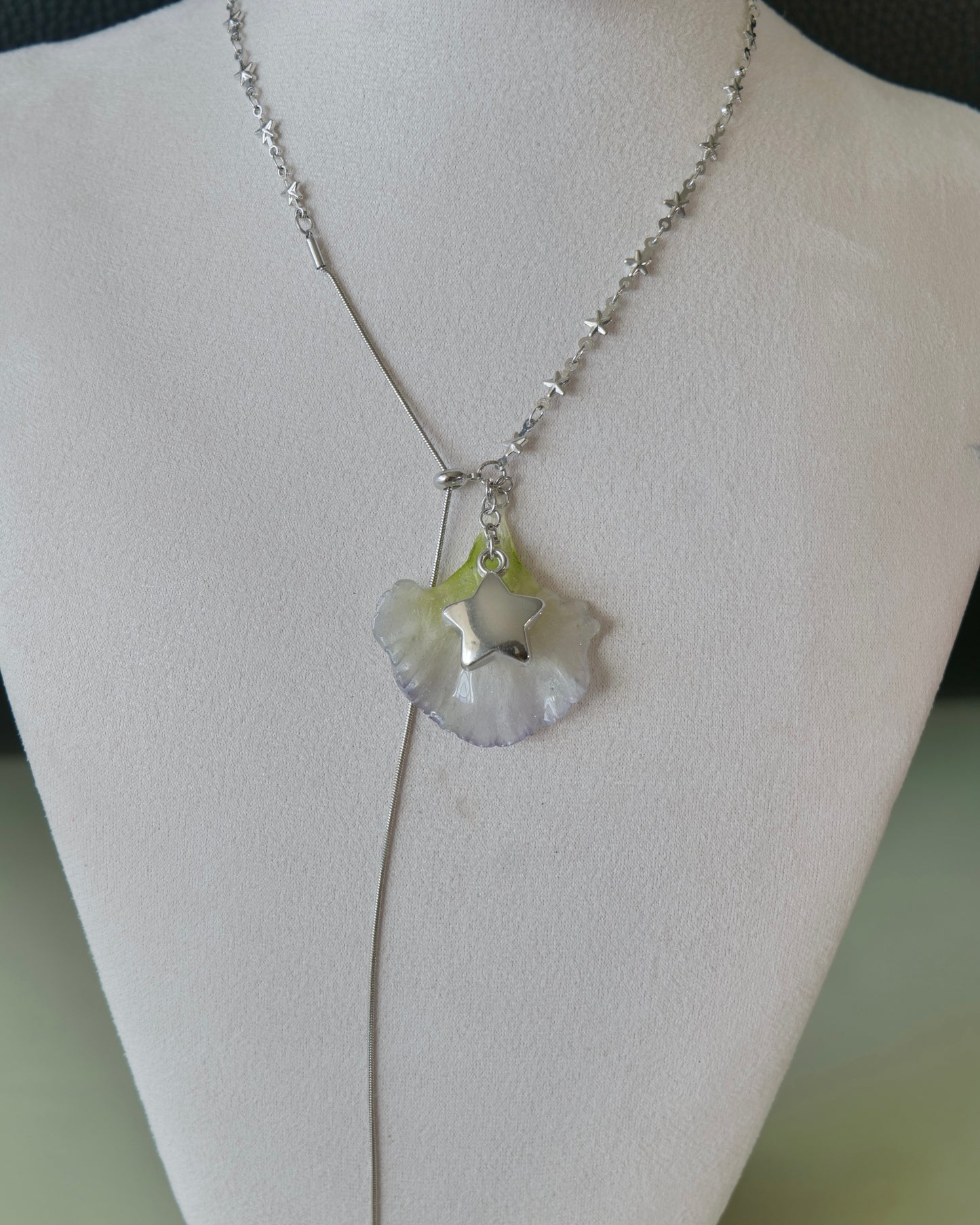 Natural-light view of translucent lisianthus petal necklace with long chain tail