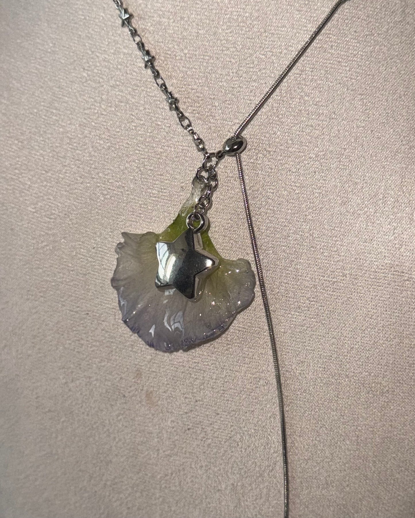 Reflective detail of preserved lisianthus petal and silver-toned star charm