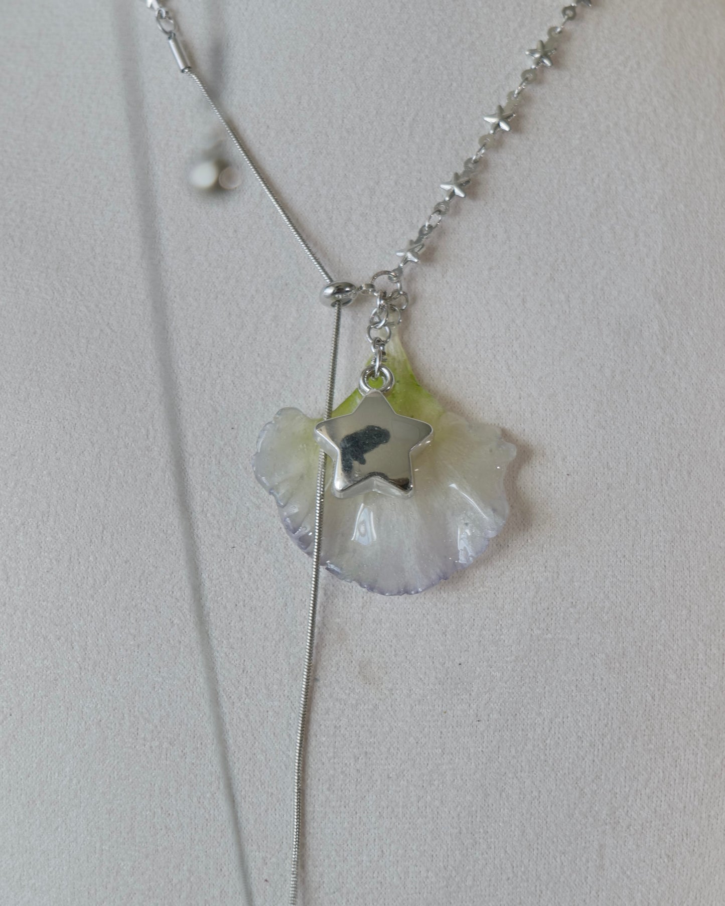Close view of translucent lisianthus petal and silver-toned star charm