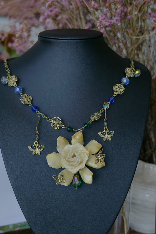 Front view of preserved gardenia necklace with antique-gold floral chain and butterfly drops