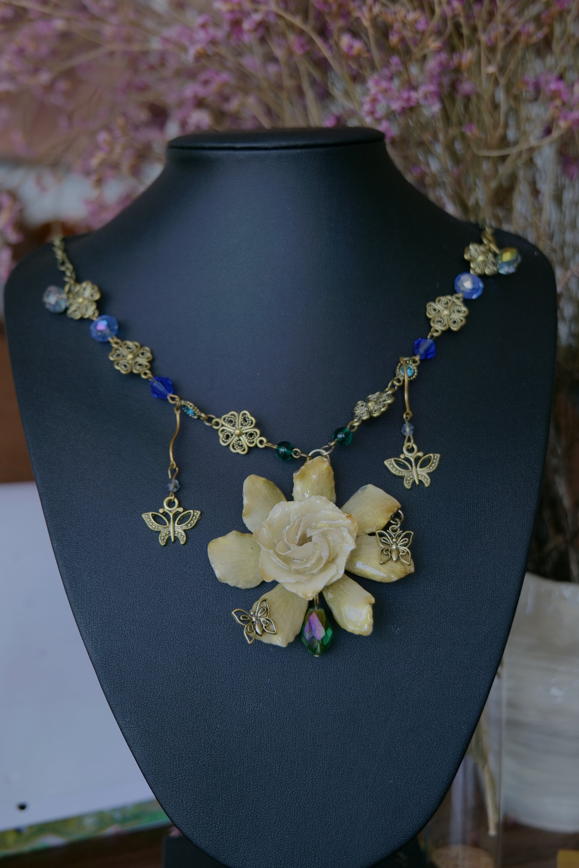 Styled view of cream gardenia necklace with blue and green crystal-style beads