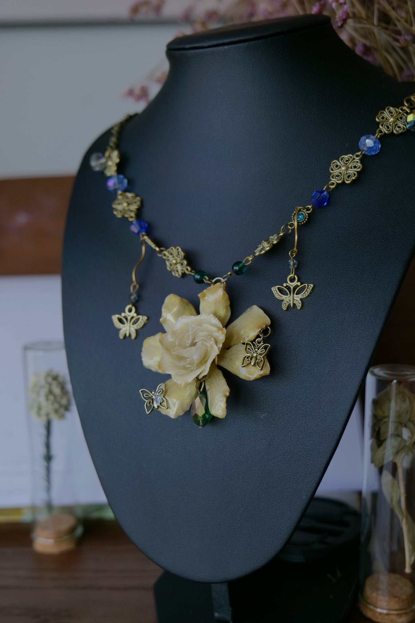 Close-up of blue and green crystal-style beads beside the preserved gardenia