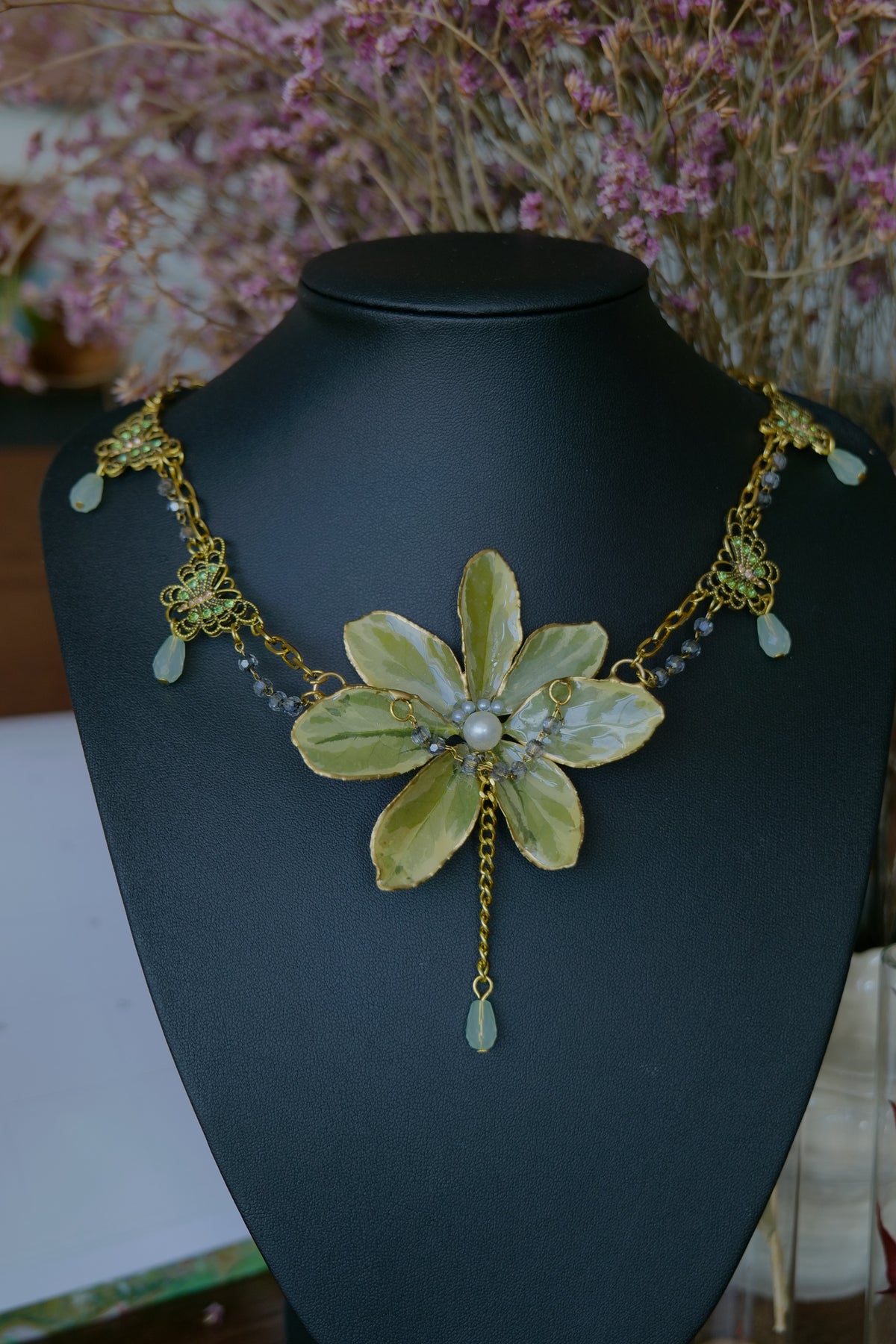 Styled view of variegated Euonymus necklace with pearl-style and pale-green drops