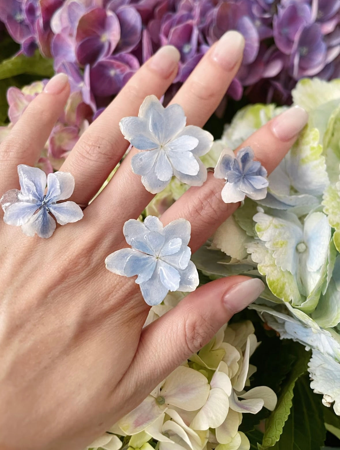 Soft pink hydrangea ring variations with resin petals against a botanical background by Terra Decode