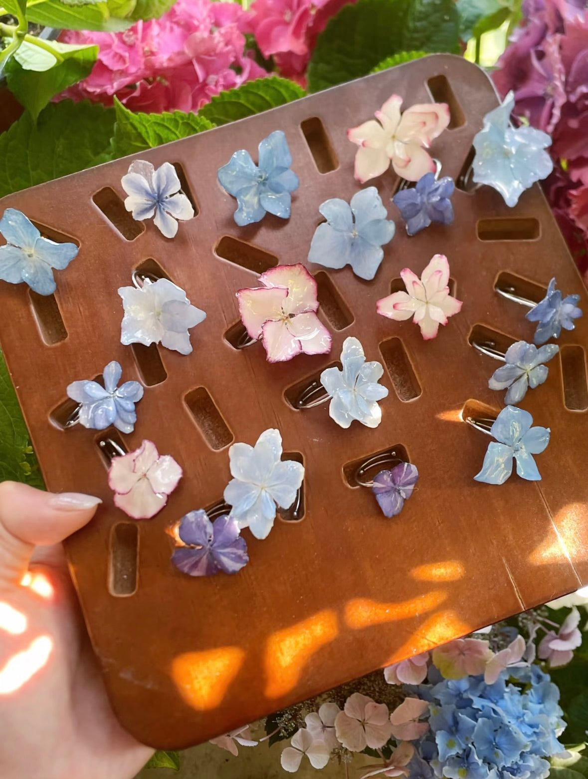 Hydrangea ring variations with resin flower petals arranged on a wooden tray by Terra Decode
