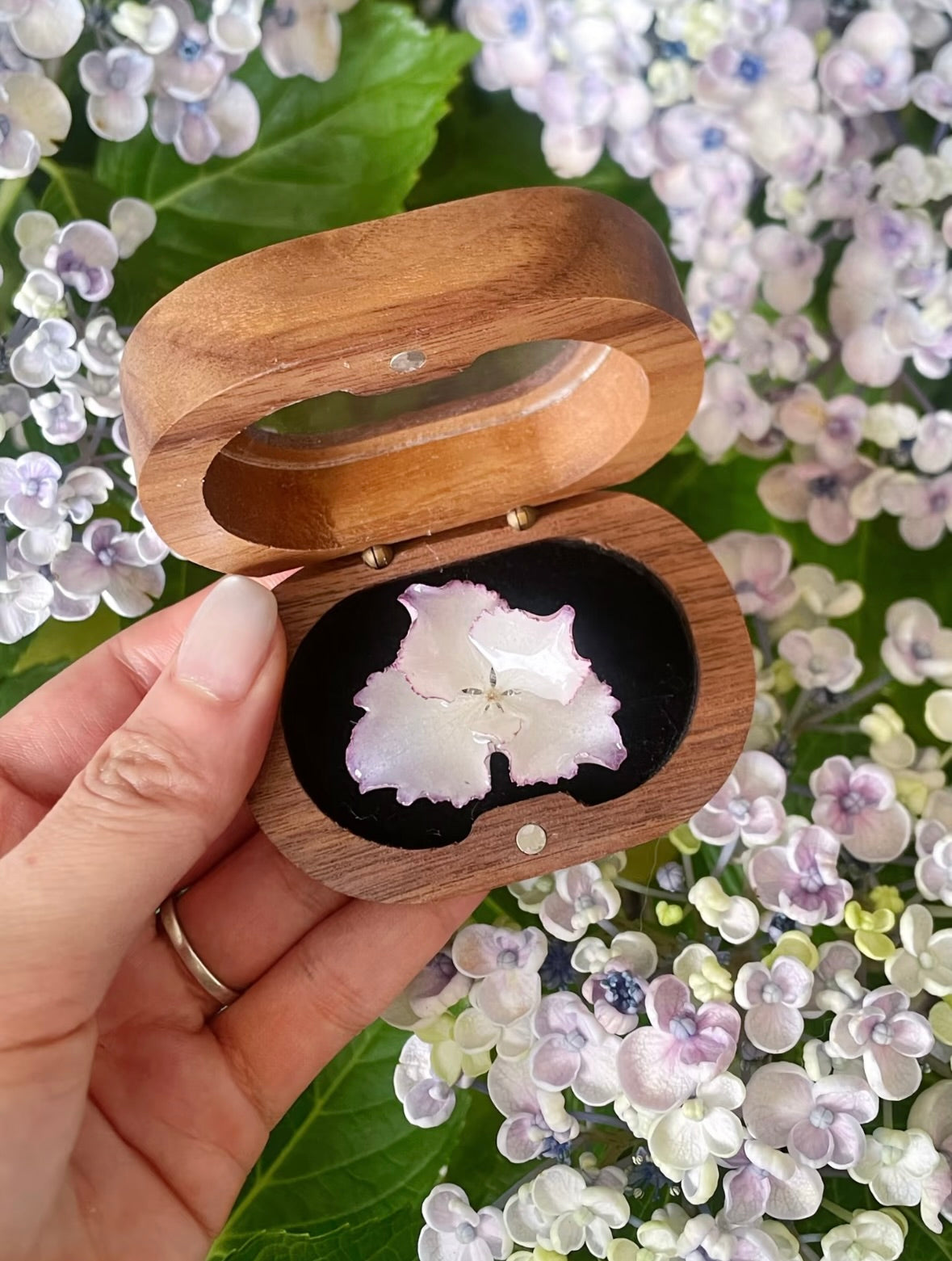 Soft pink hydrangea ring with resin petals displayed in a wooden jewellery box by Terra Decode