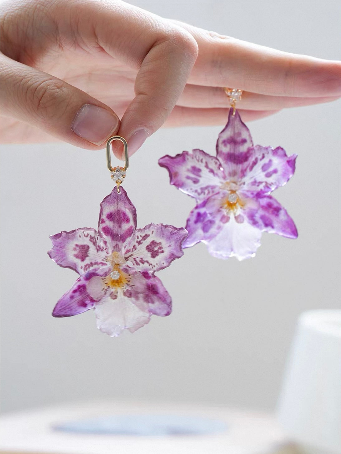 Spotted purple orchid earrings with resin petals held in hand by Terra Decode