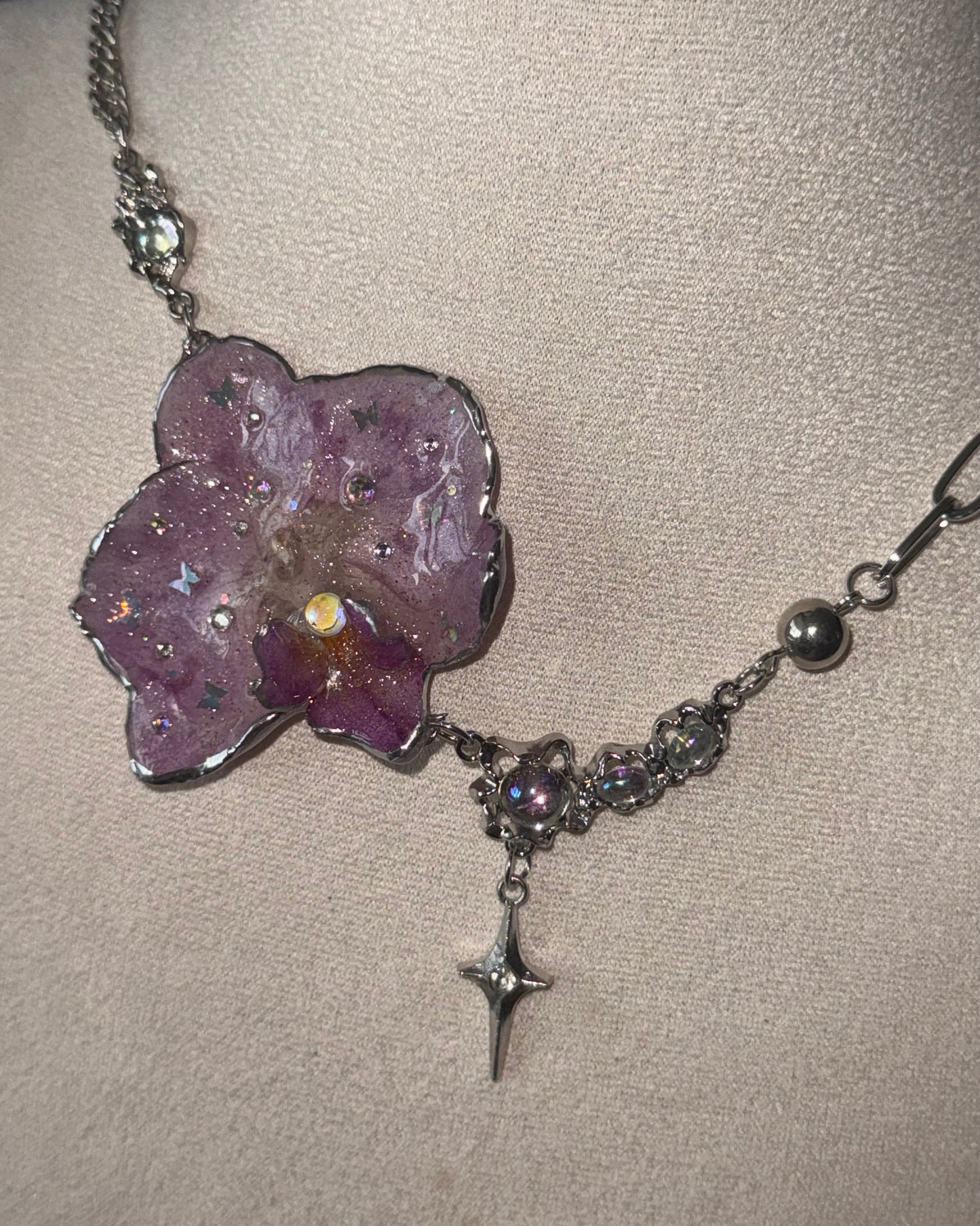 Reflective detail of lilac phalaenopsis pendant, iridescent accents and silver-toned star