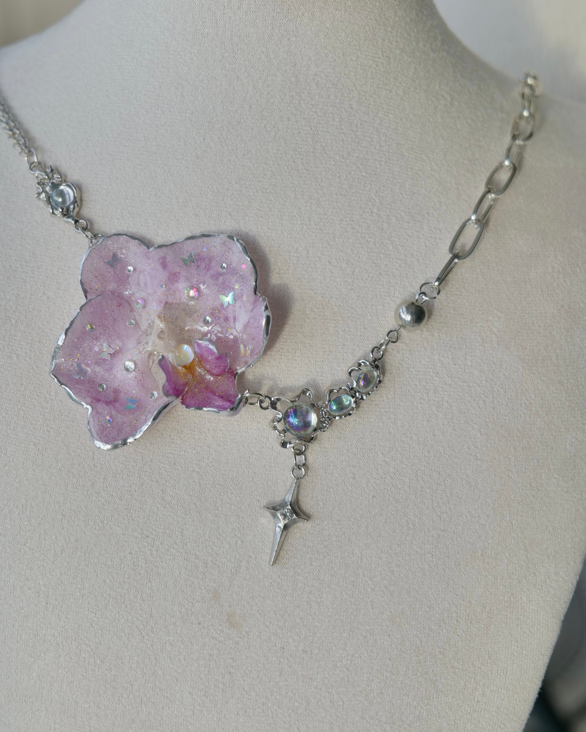 Angled view of the Lilac Phalaenopsis Moonstone Star-Drop Necklace showing asymmetric chains