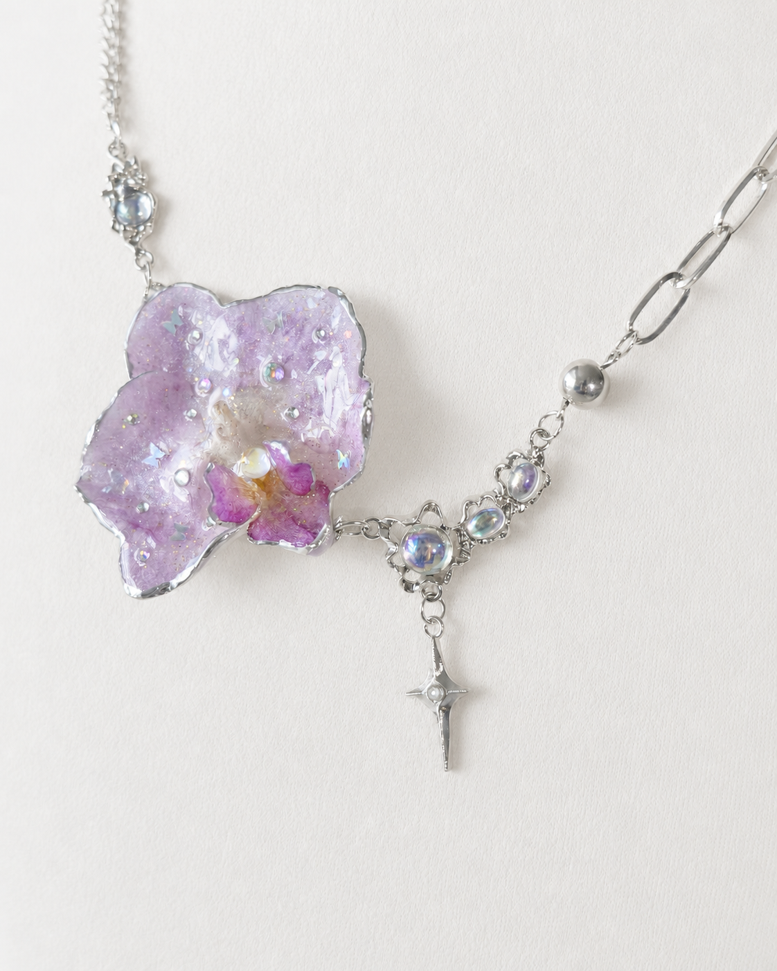 Detailed view of the real Phalaenopsis orchid preserved in clear resin, Lilac Phalaenopsis Moonstone-Style Star-Drop Necklace botanical jewellery by Terra Decode