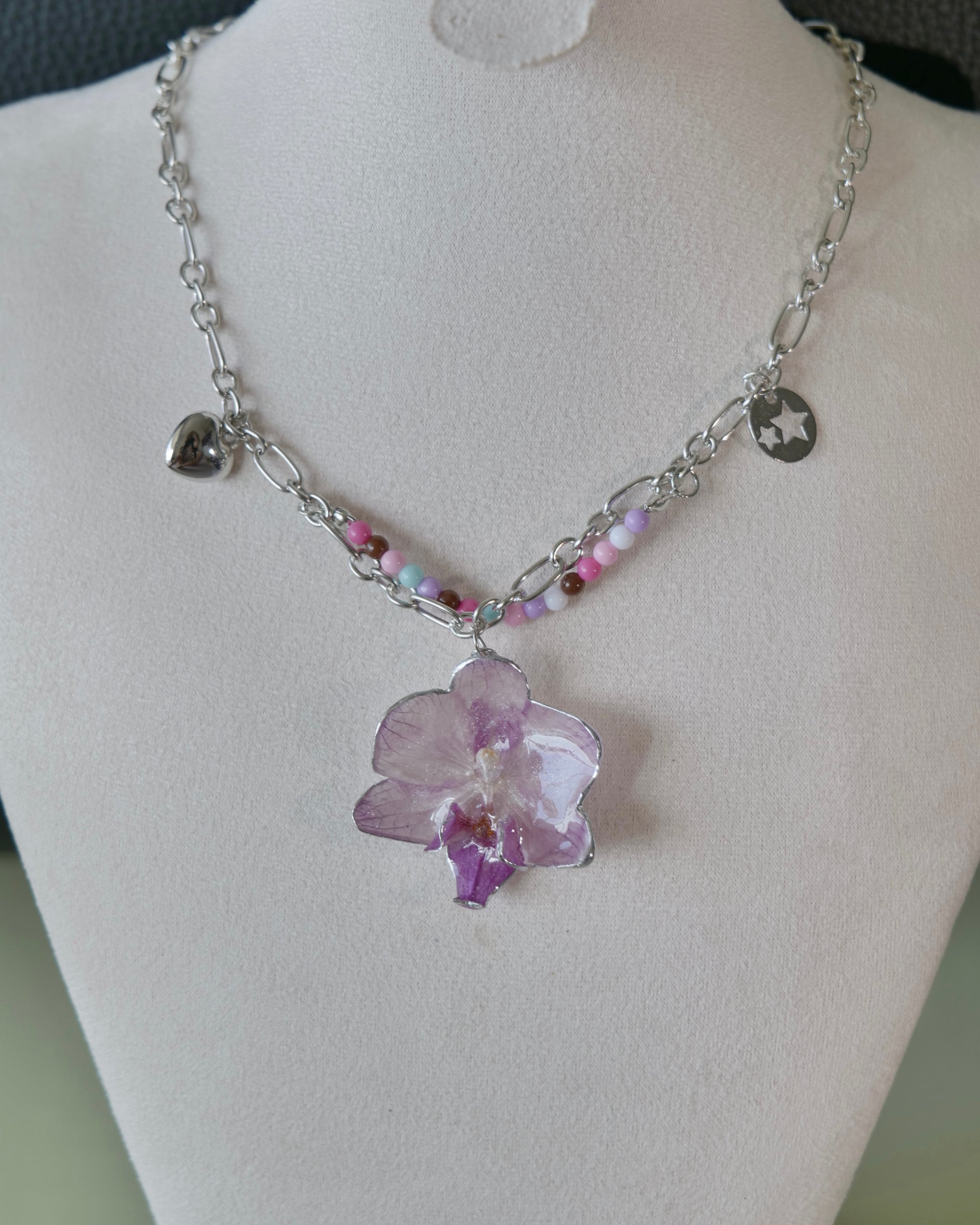Natural-light view of orchid necklace with heart and star-cutout charms