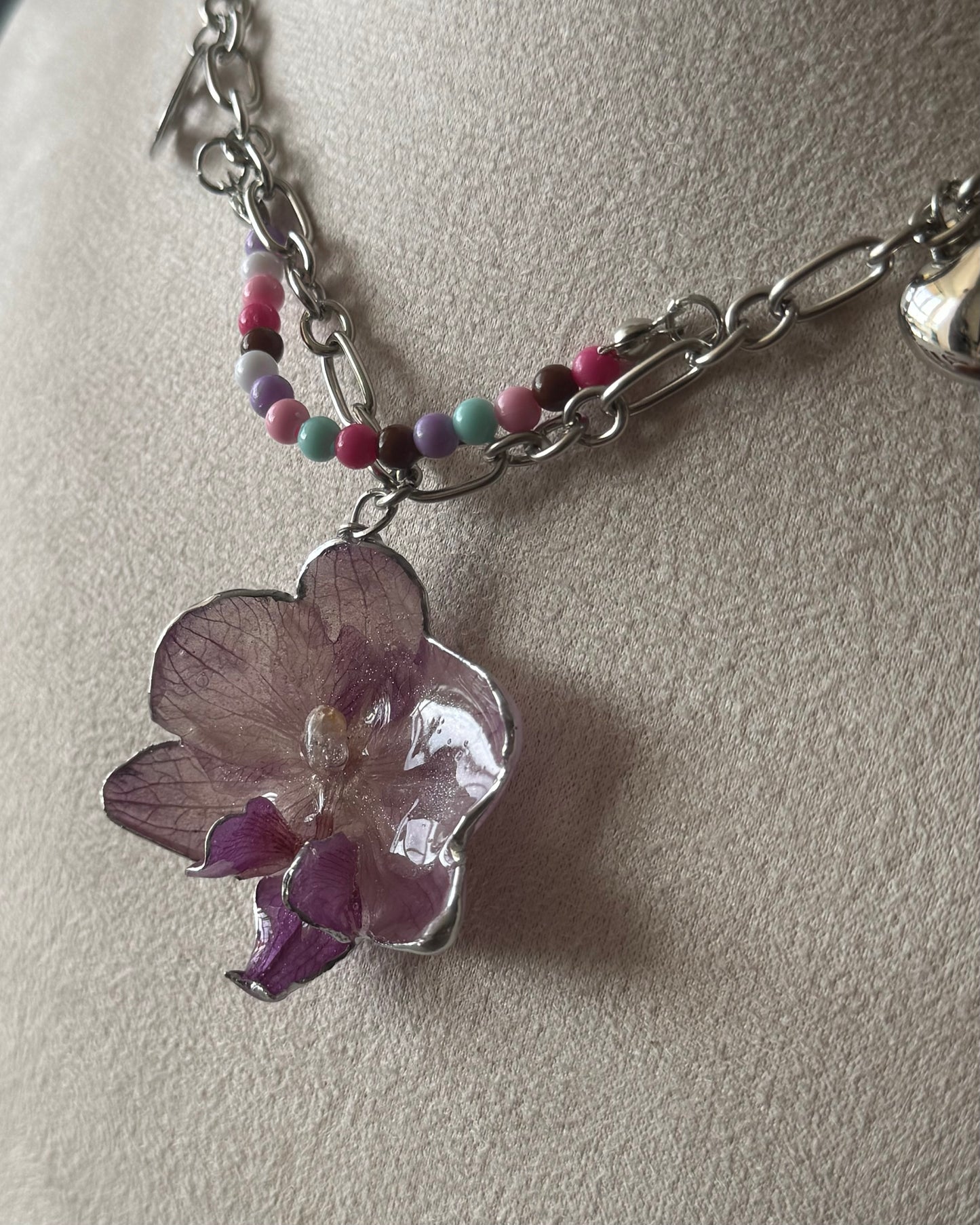 Close-up of lilac phalaenopsis resin pendant with pink and purple bead accents
