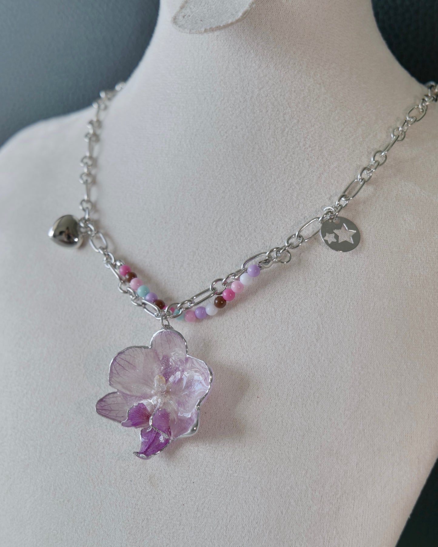 Angled view of the Lilac Phalaenopsis Pastel Bead Charm Necklace showing layered chains