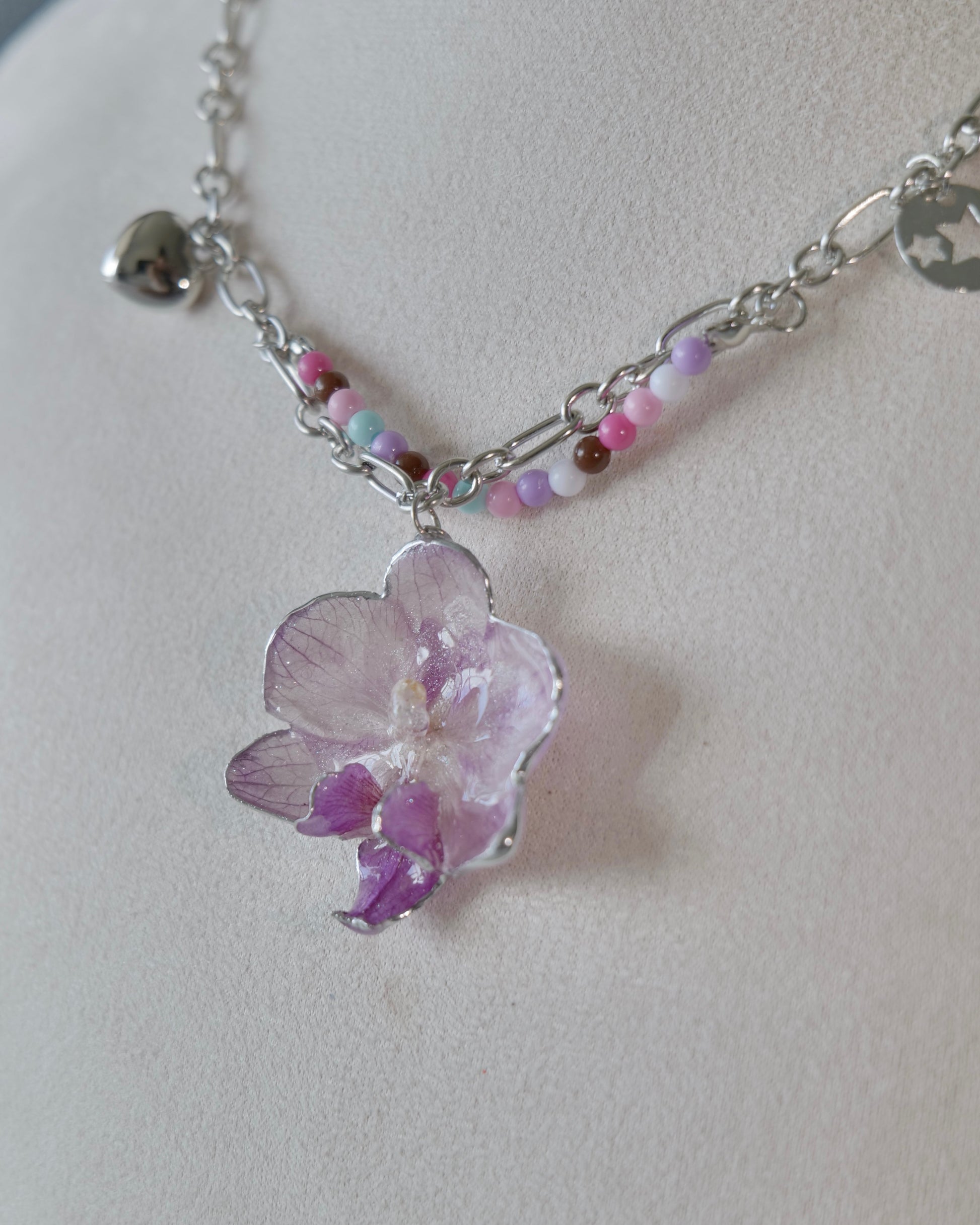 Side angle of pastel bead strand layered with silver-toned chain