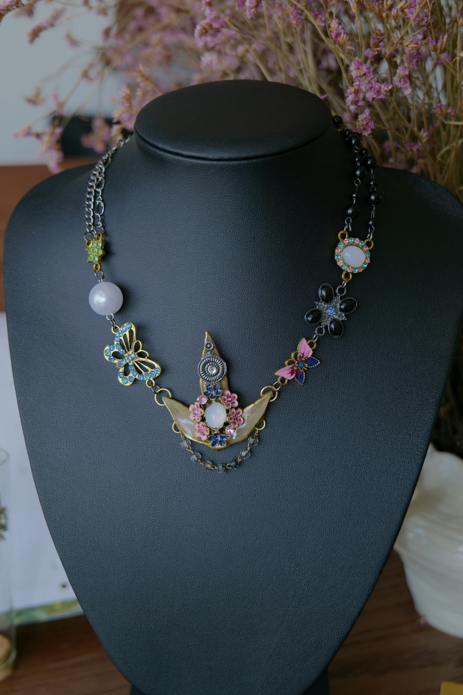 Styled view of preserved Nandina necklace with butterfly, floral and pearl-style charms