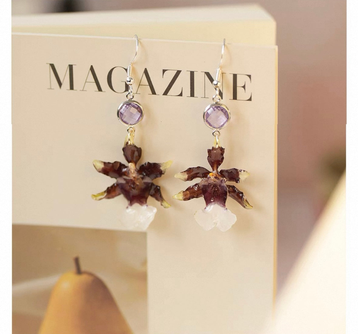 Deep plum oncidium orchid earrings with resin petals on an editorial card by Terra Decode