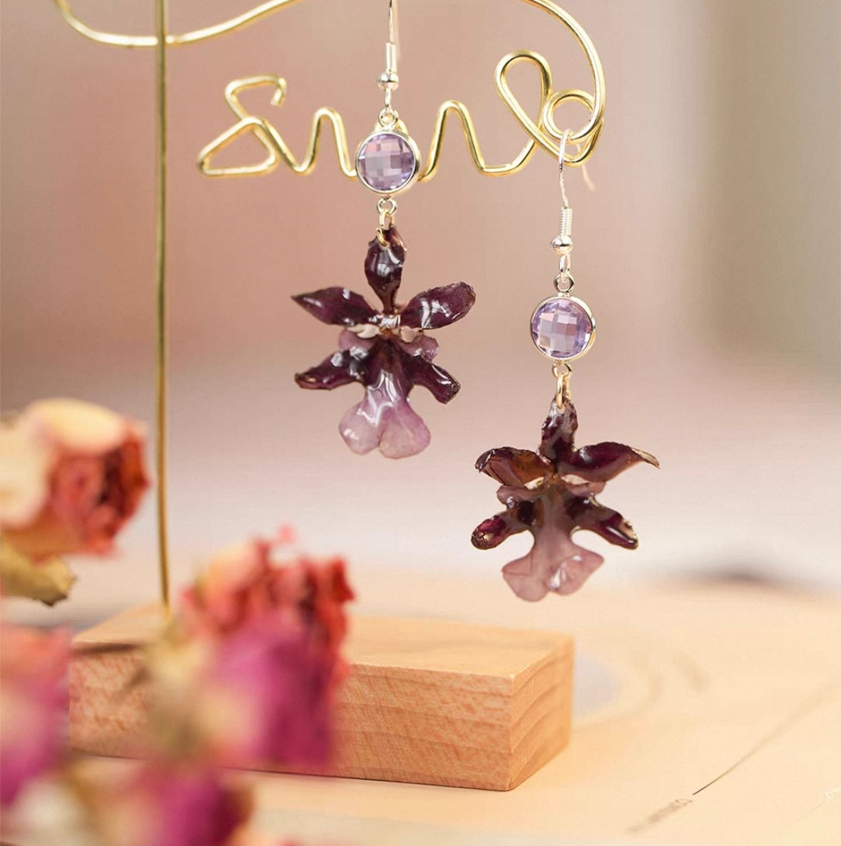 Deep plum oncidium orchid earrings with resin flower petals and warm display styling by Terra Decode