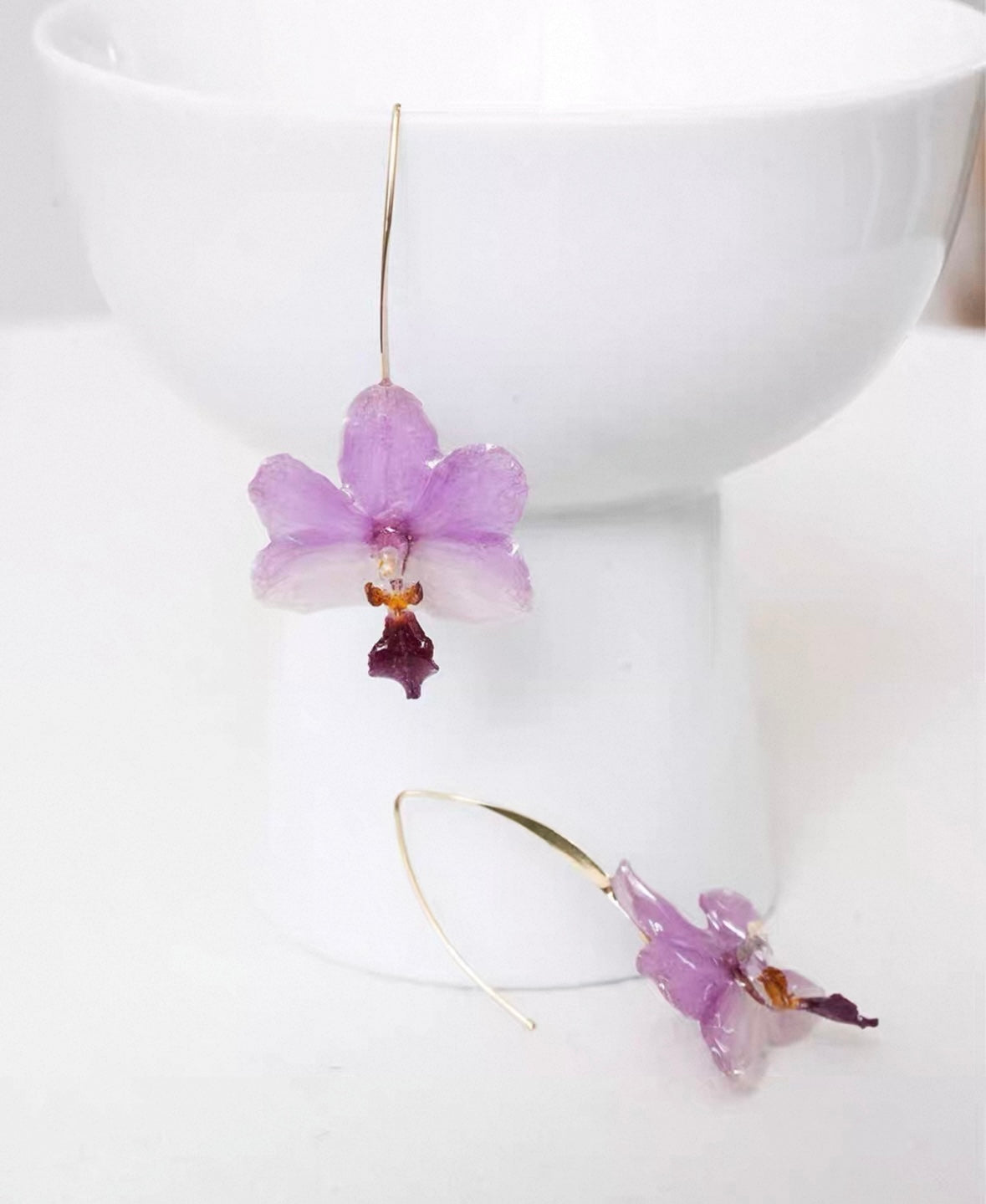 Soft purple orchid ear hook earrings with resin petals on an editorial page by Terra Decode