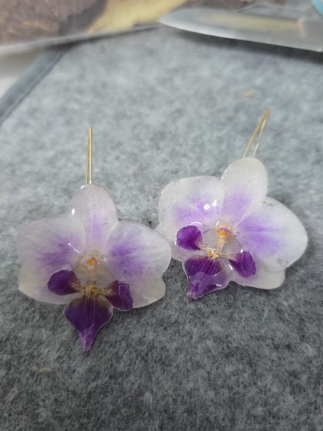 Soft purple orchid ear hook earrings with resin petals on grey felt by Terra Decode