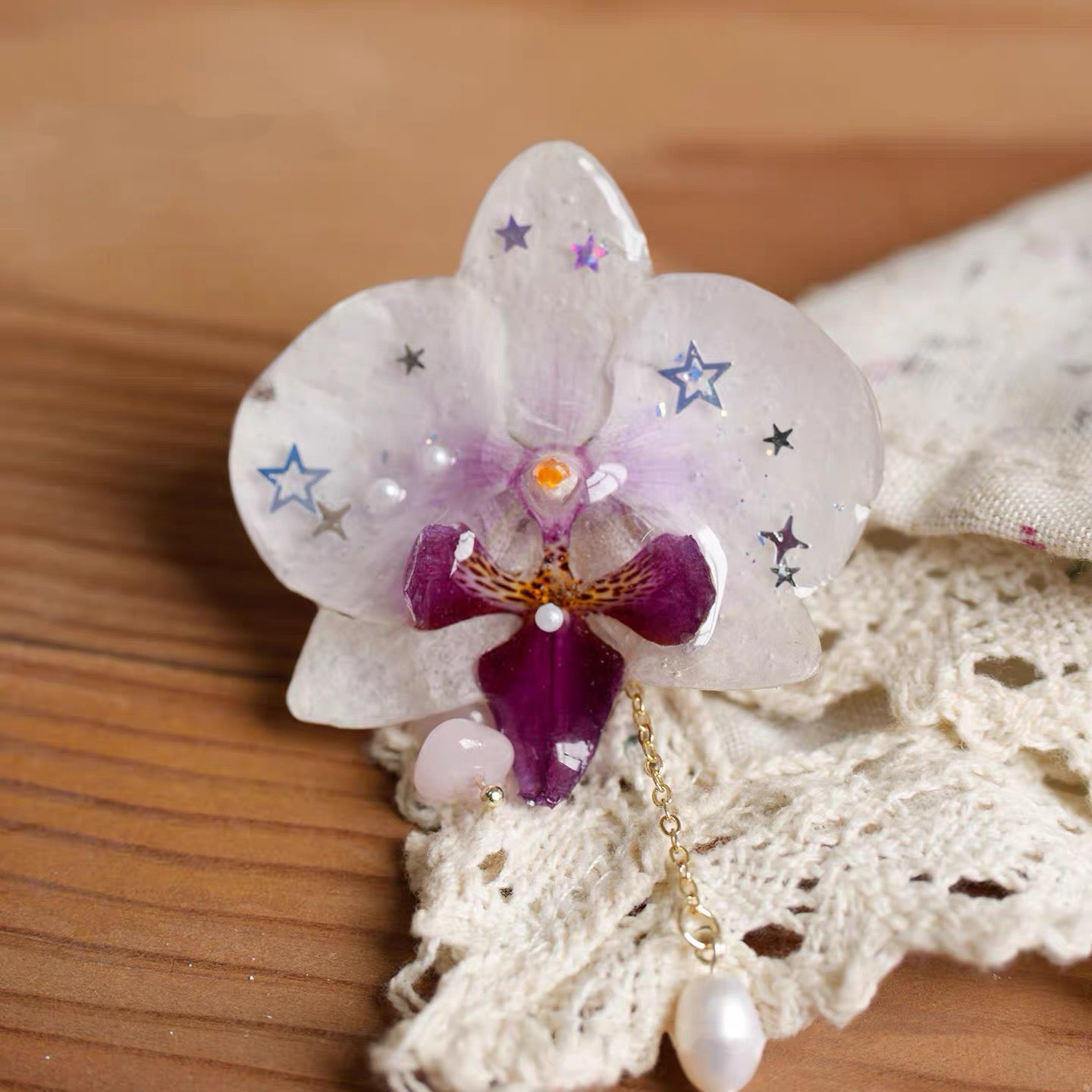 Star detail orchid brooch with resin petals, star-like accents and pearl-like drops by Terra Decode