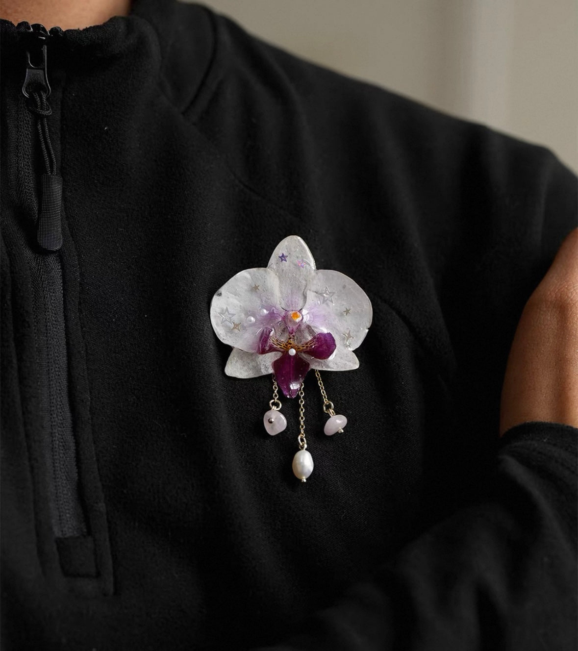 White pearl detail orchid brooch with resin petals worn on black top by Terra Decode
