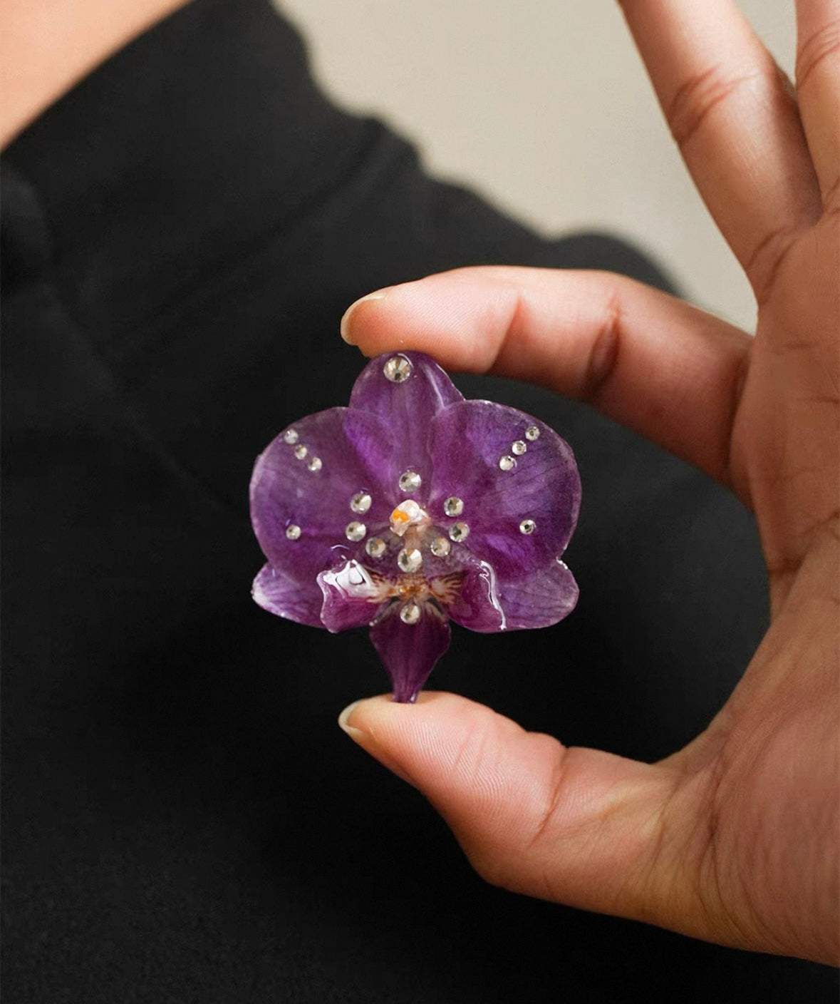 Star detail orchid brooch with resin petals and crystal-like accents held in hand by Terra Decode