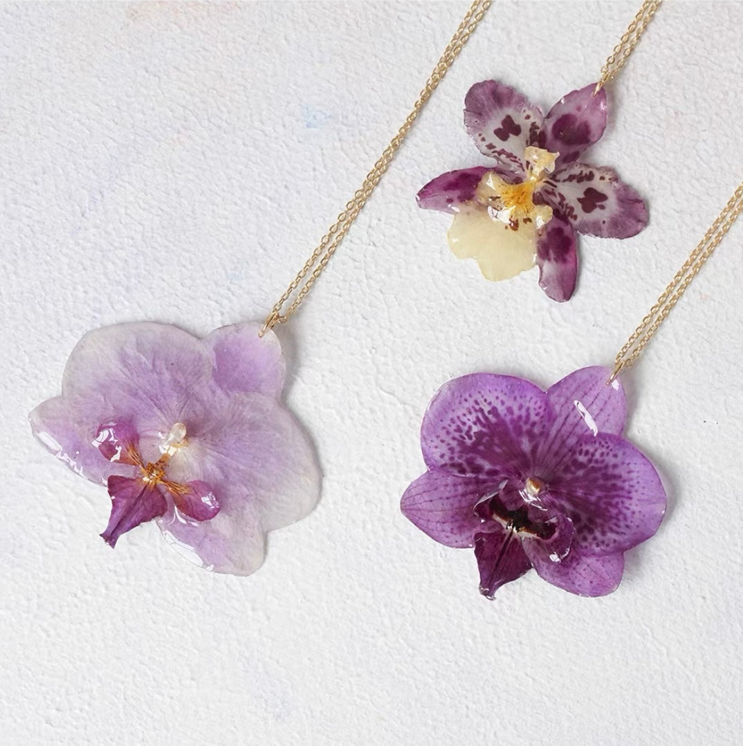 Soft purple orchid necklace variations with resin flower pendants and gold-tone chains by Terra Decode