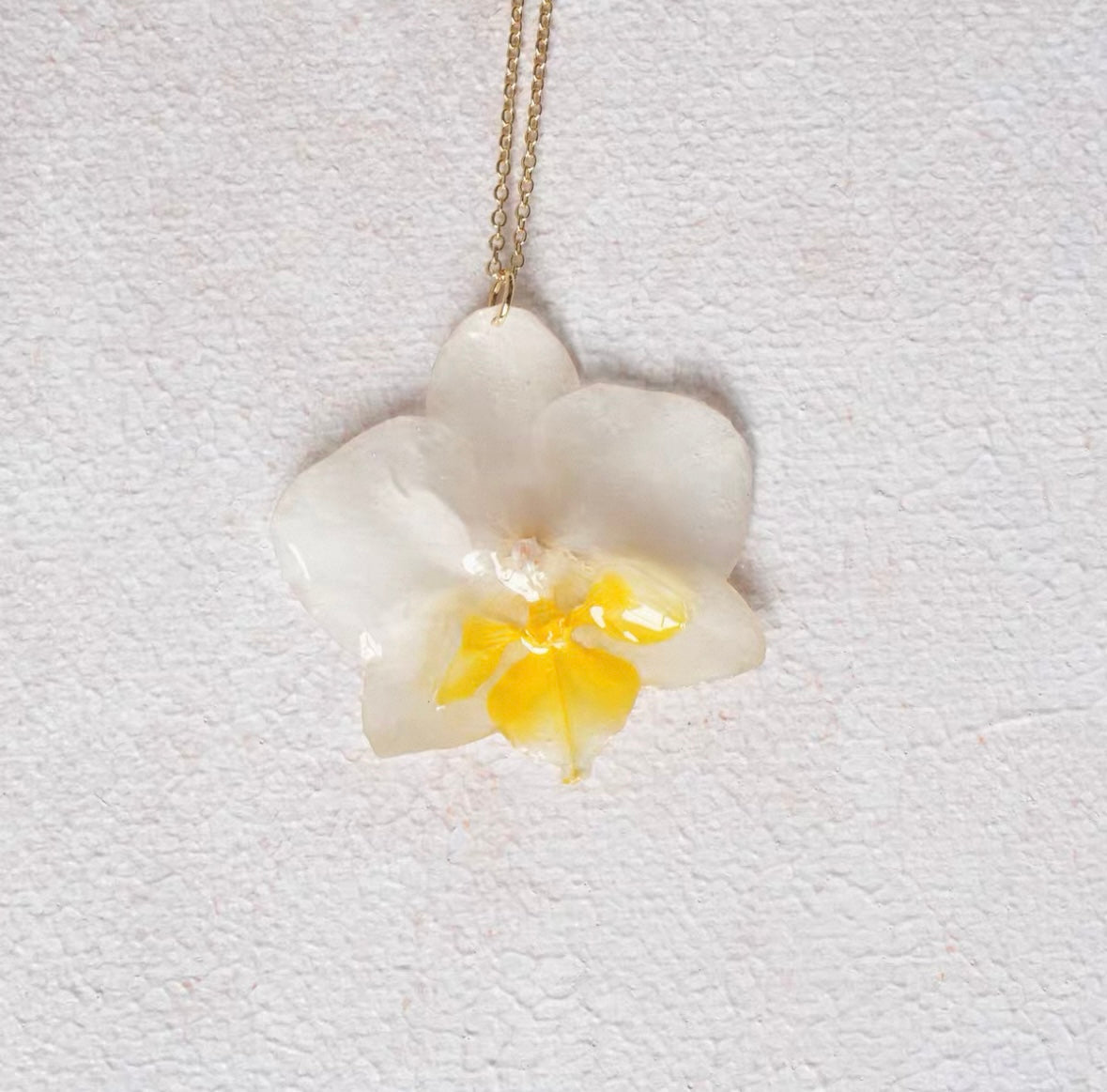 Cream white orchid pendant necklace with resin petals and gold-tone chain by Terra Decode
