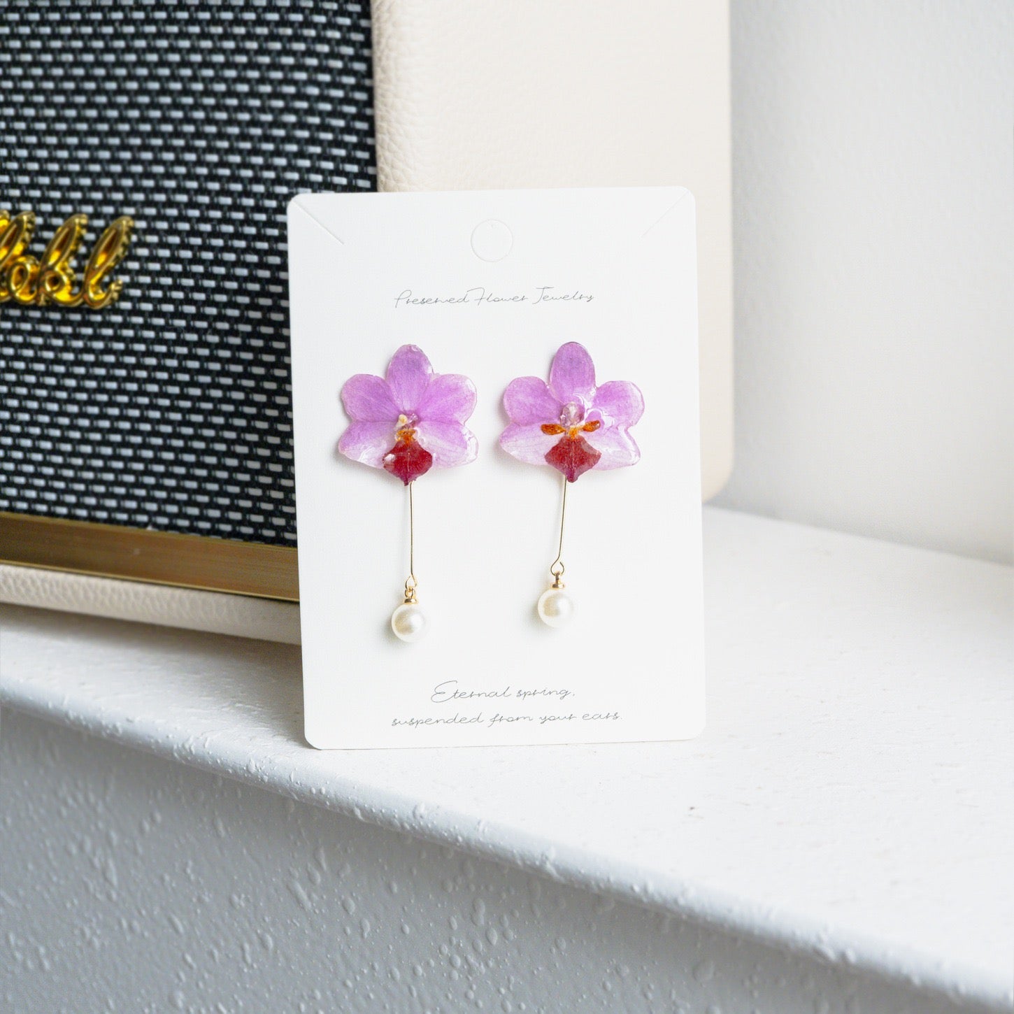 Soft pink orchid earrings with resin petals displayed on a jewellery card by Terra Decode