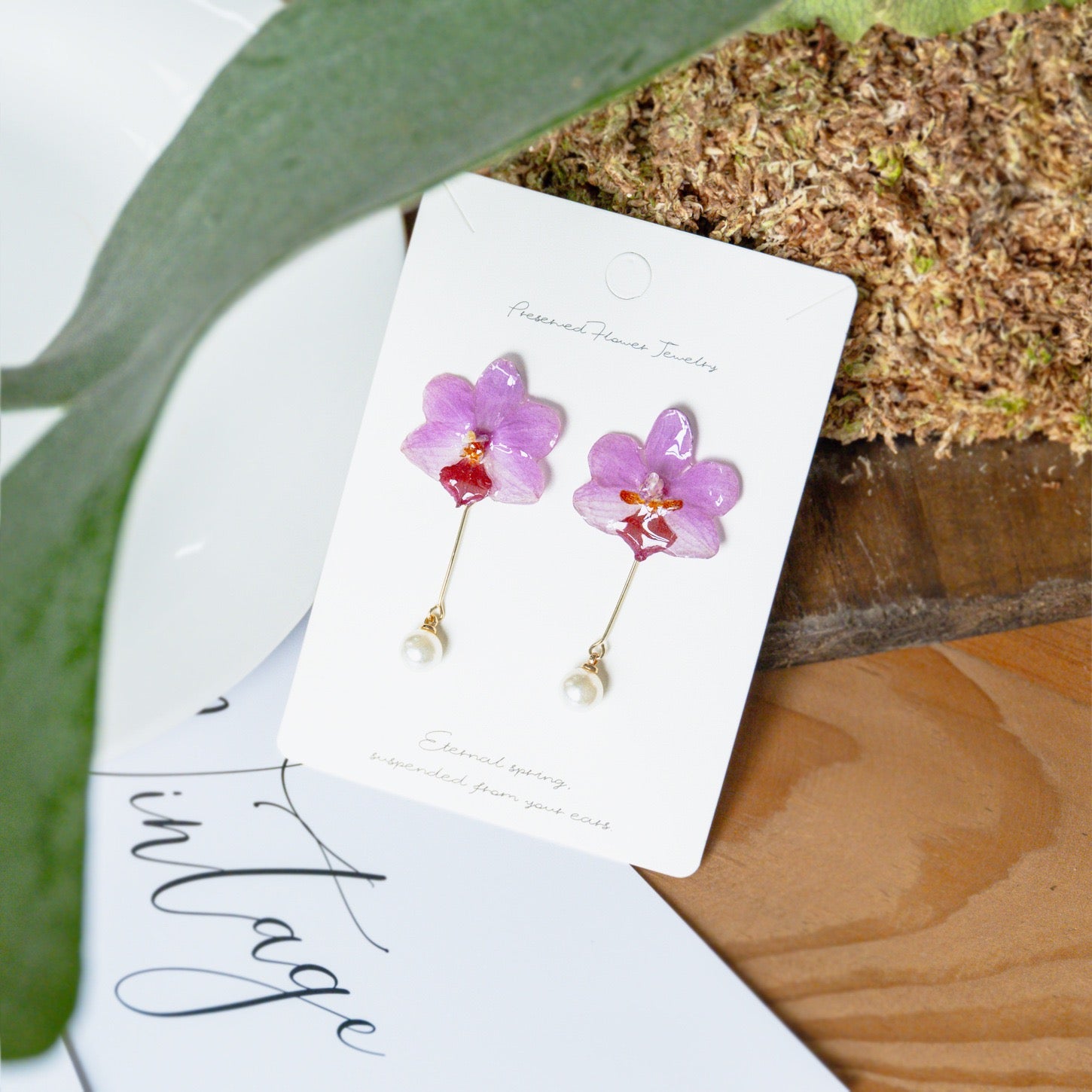 Soft pink orchid earrings with resin flower petals and botanical styling by Terra Decode