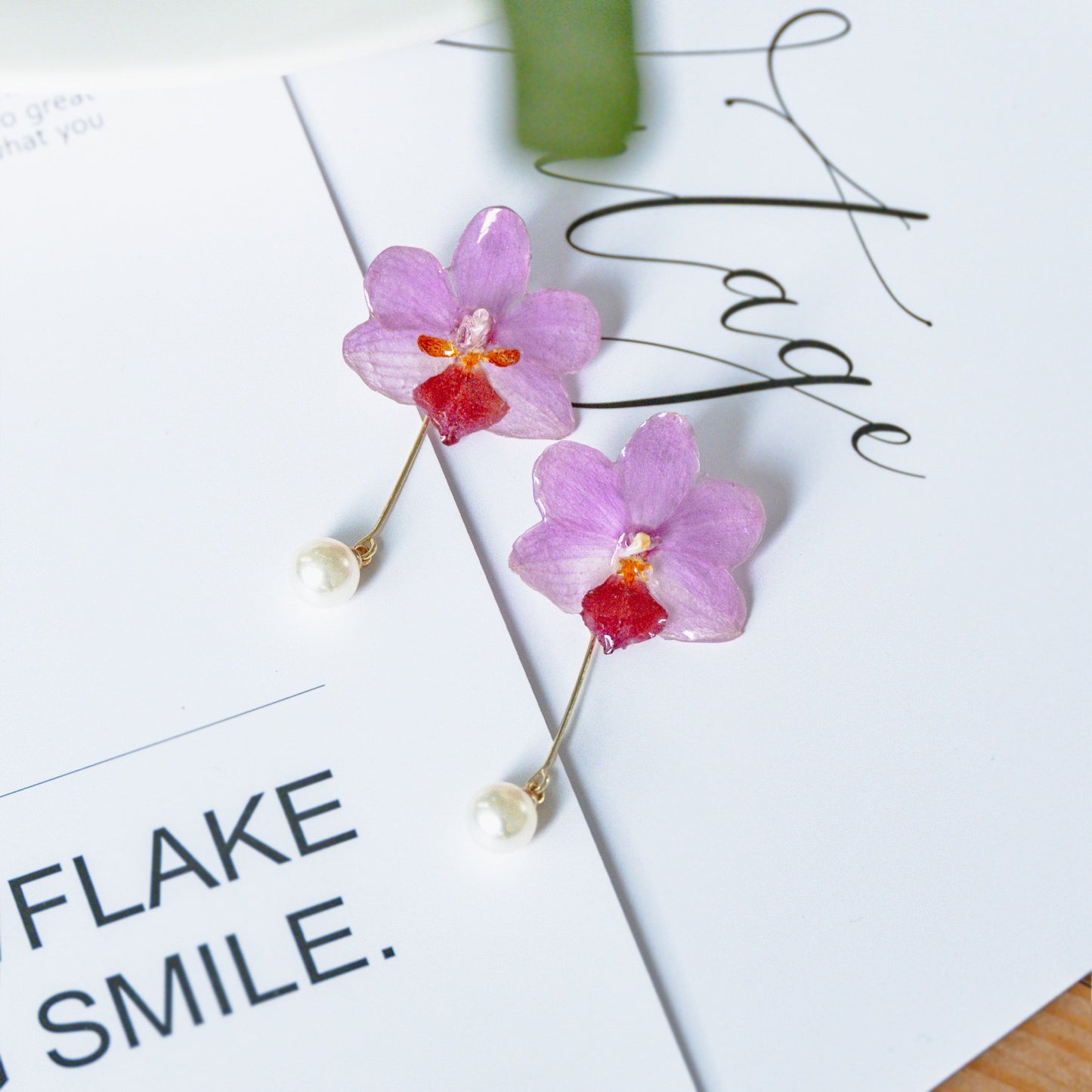 Soft pink orchid earrings with resin petals on an editorial page by Terra Decode