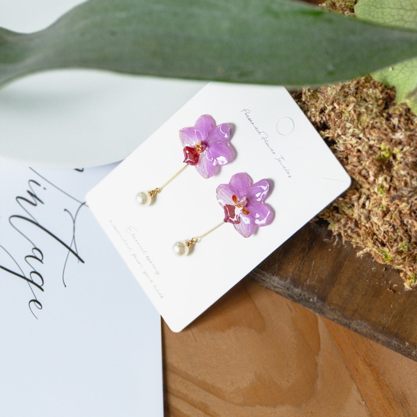 Soft pink orchid pearl drop earrings with resin petals on a jewellery card by Terra Decode