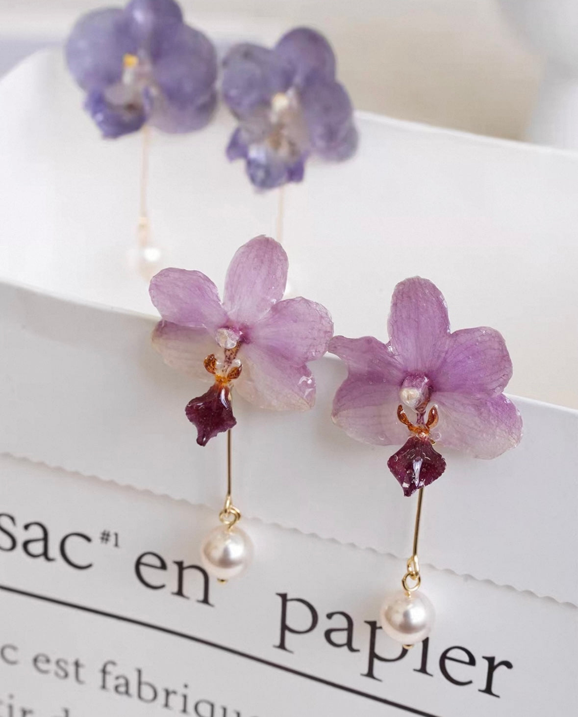 Soft pink and lavender orchid pearl drop earrings with resin petals on printed paper by Terra Decode
